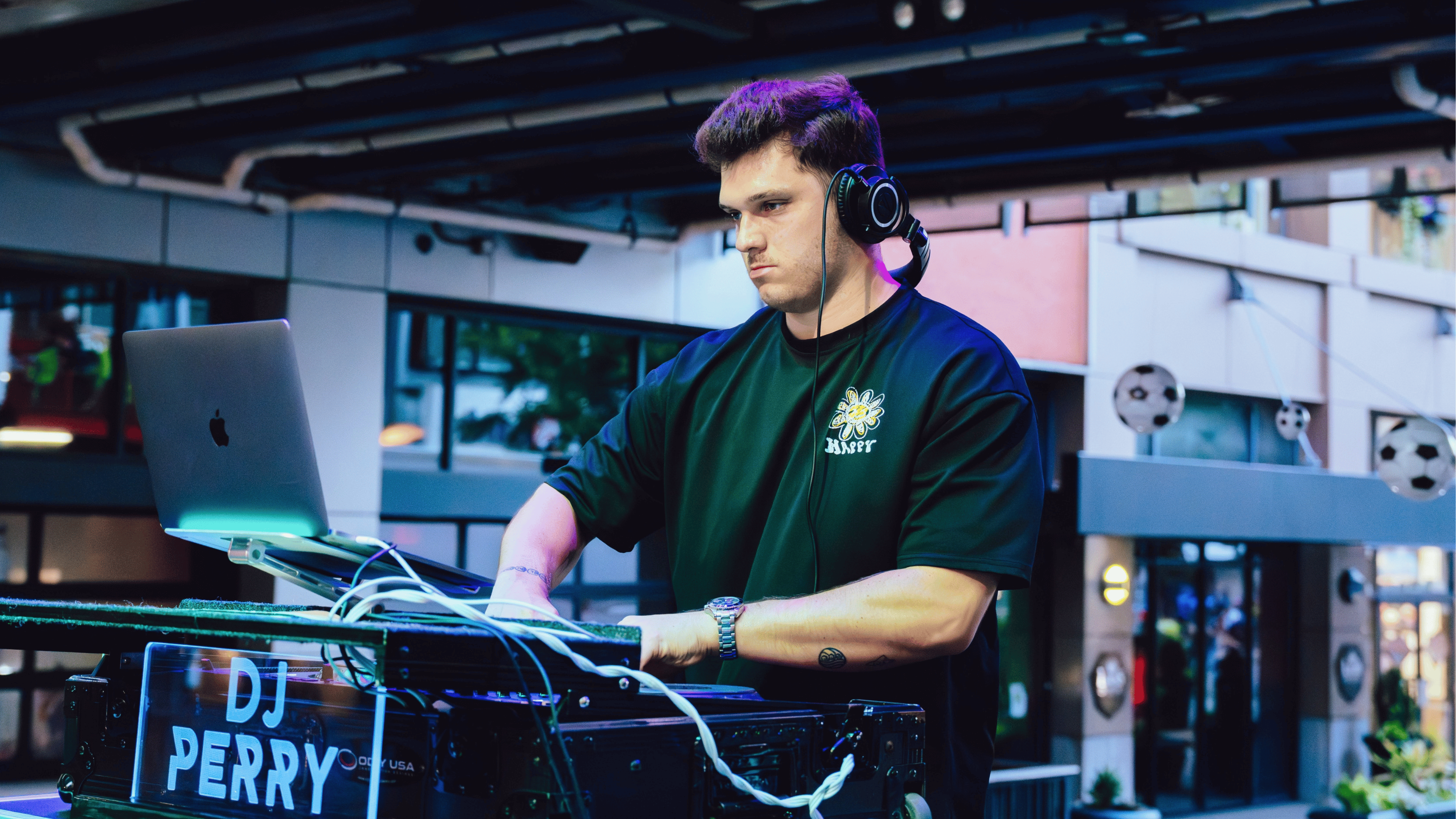 An image of a man, DJ Perry, wearing a black shirt and djing.