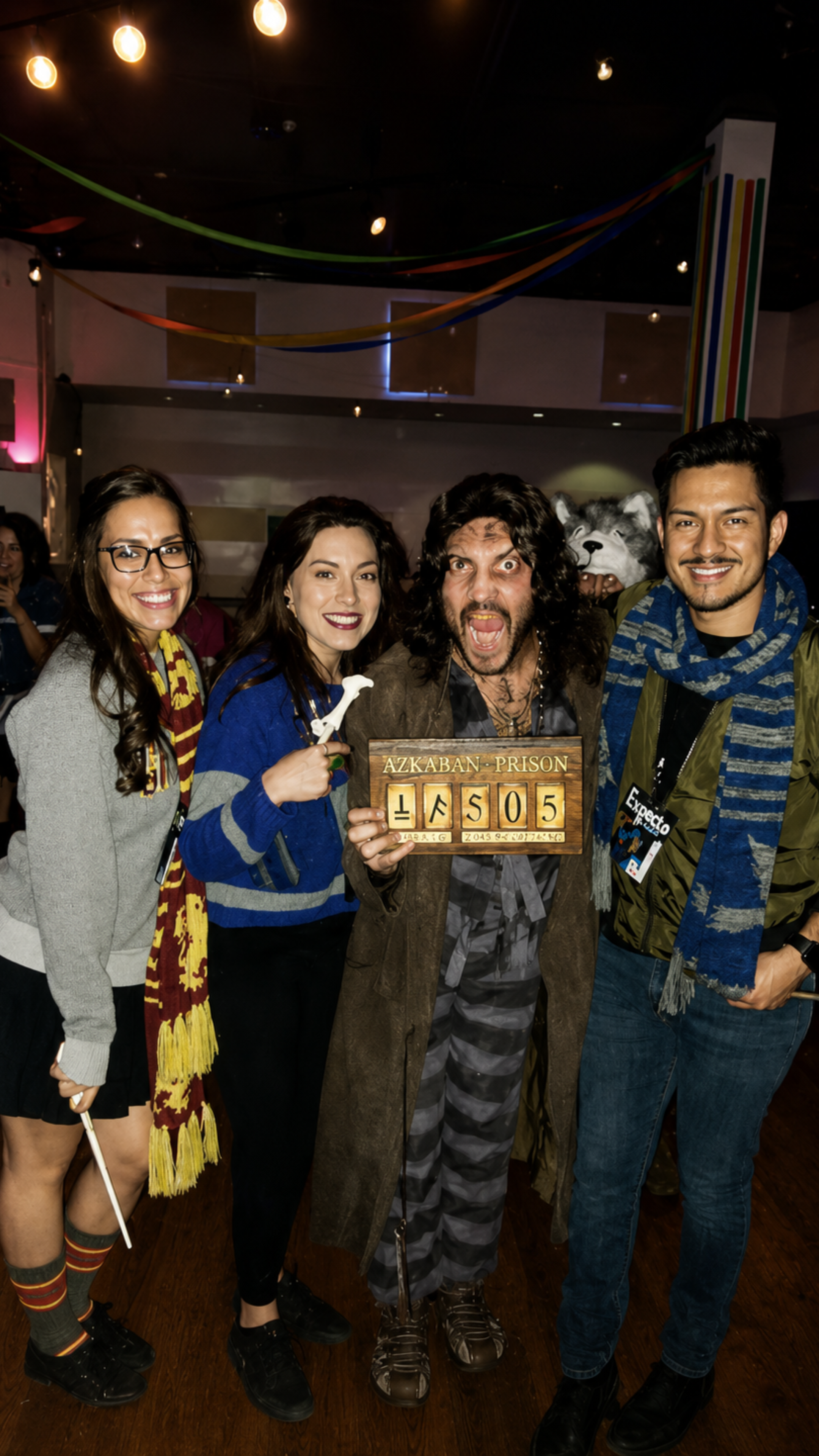 An image of four people posing for a ;picture and wearing Harry Potter costumes.