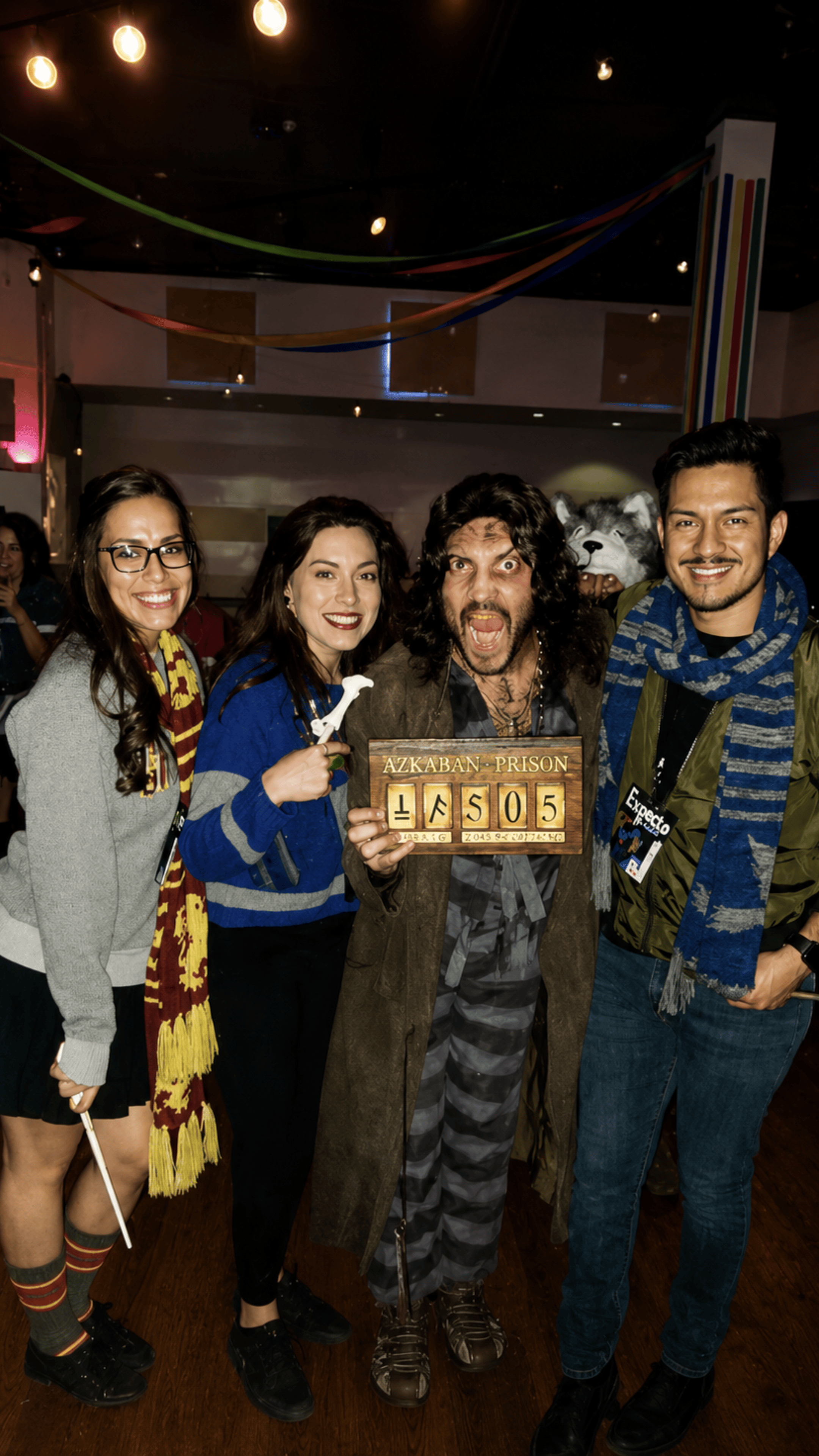 An image of four people posing for a ;picture and wearing Harry Potter costumes.