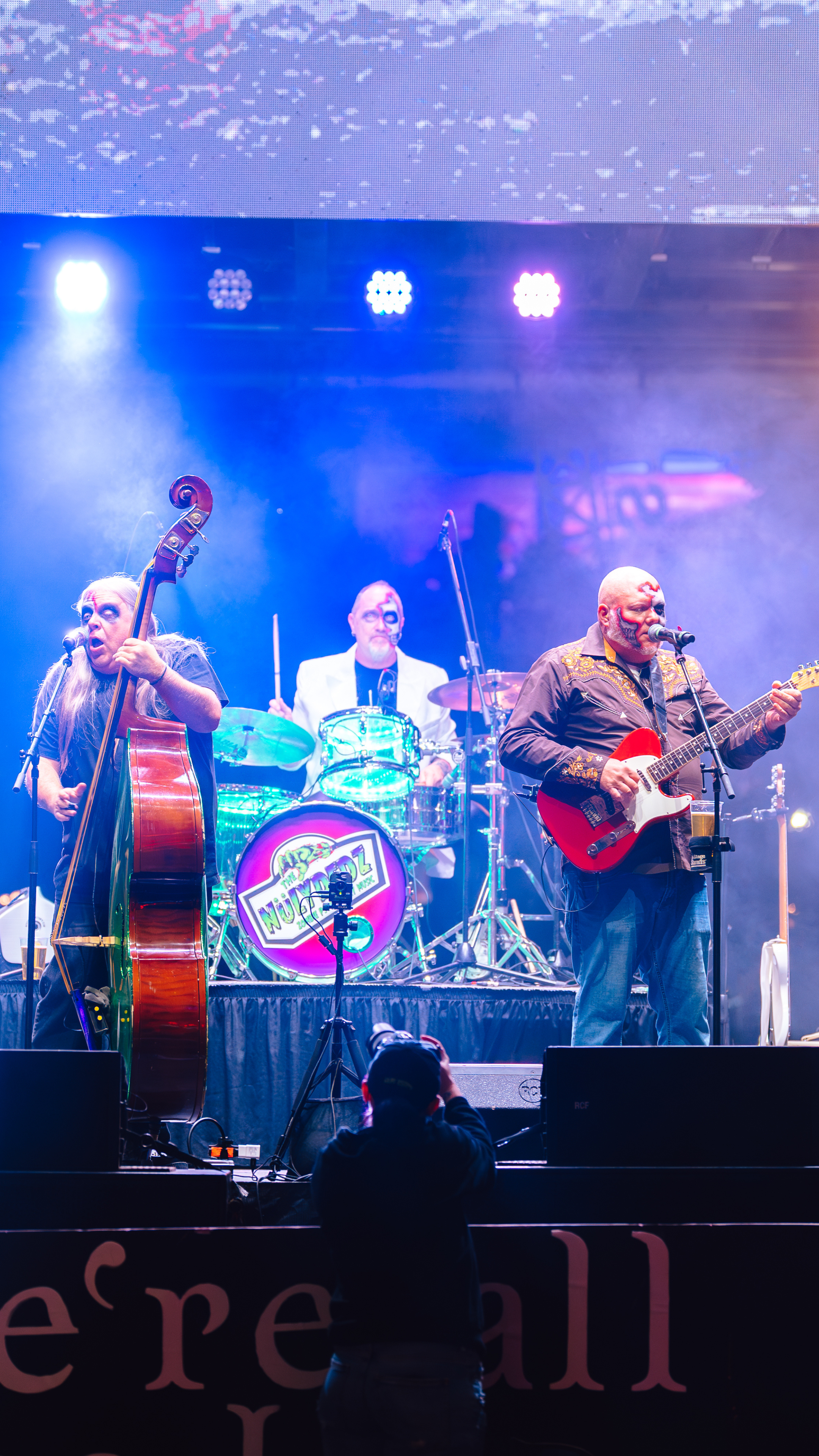 An image of a band in zombie makeup on stage playing instruments.
