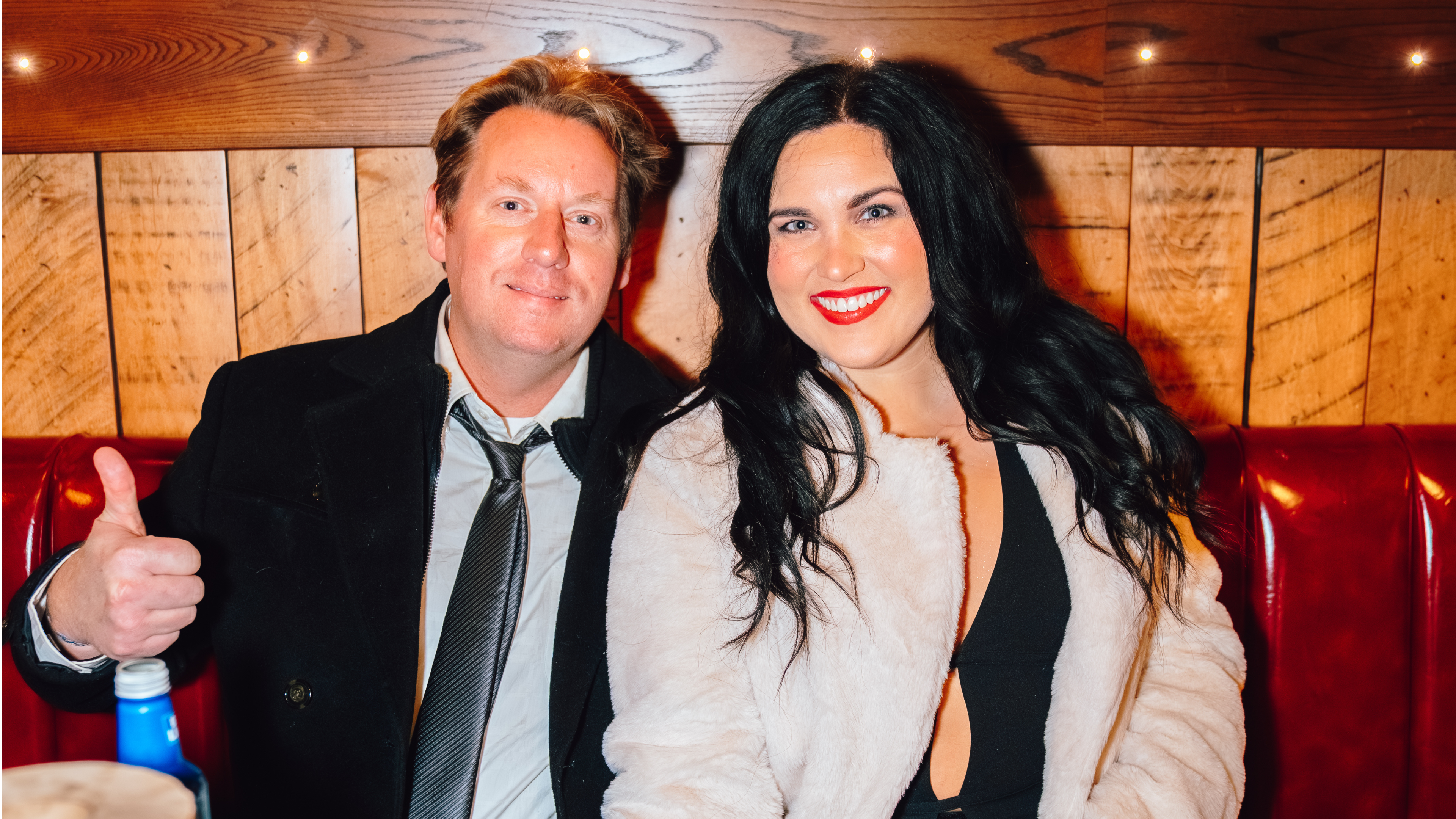 An image of a man and woman sitting at a table and posing for a picture at Guy Fieri's Smokehouse.