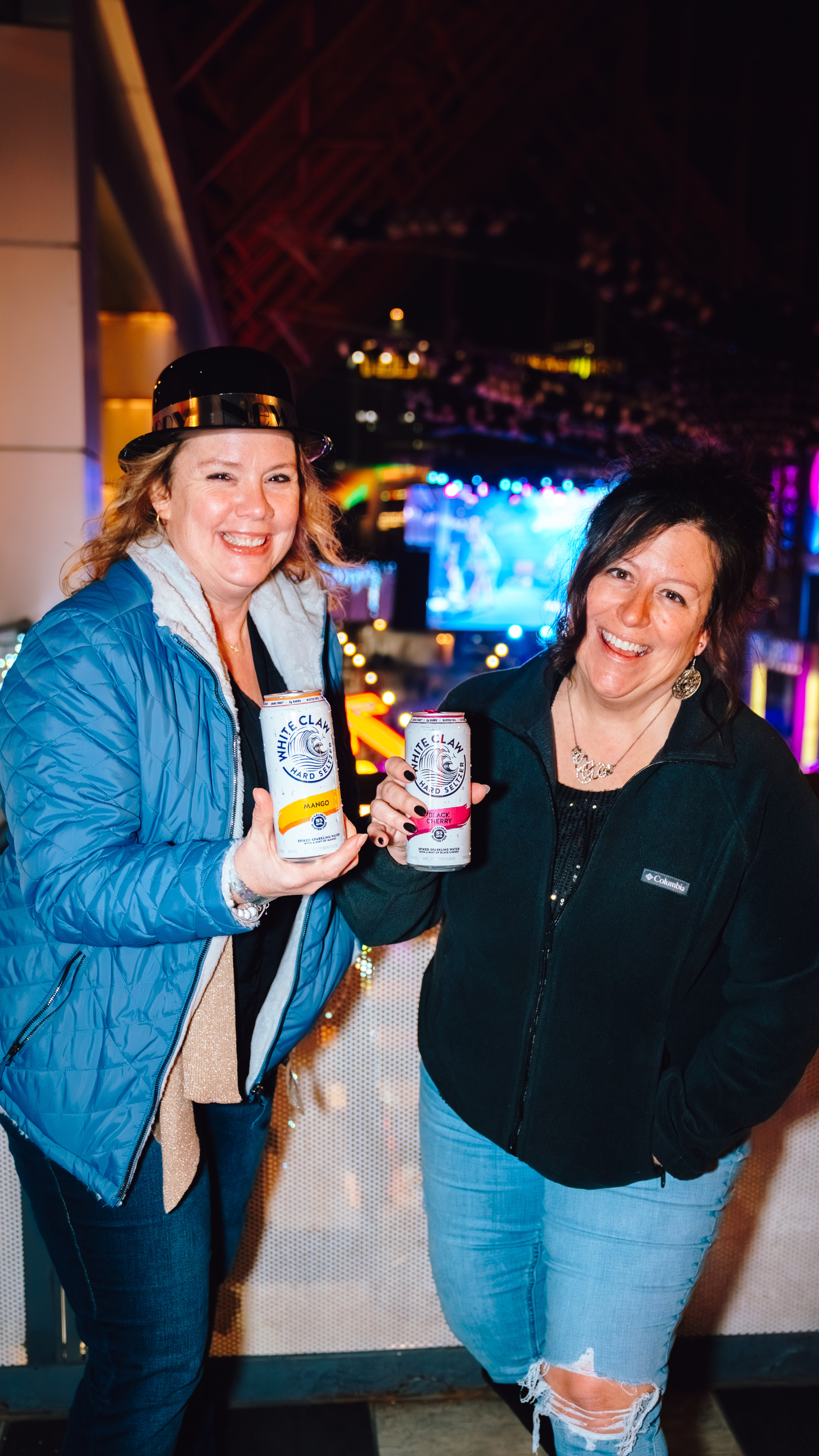 An image of two women at the NYE Party holding cans of White Claw.