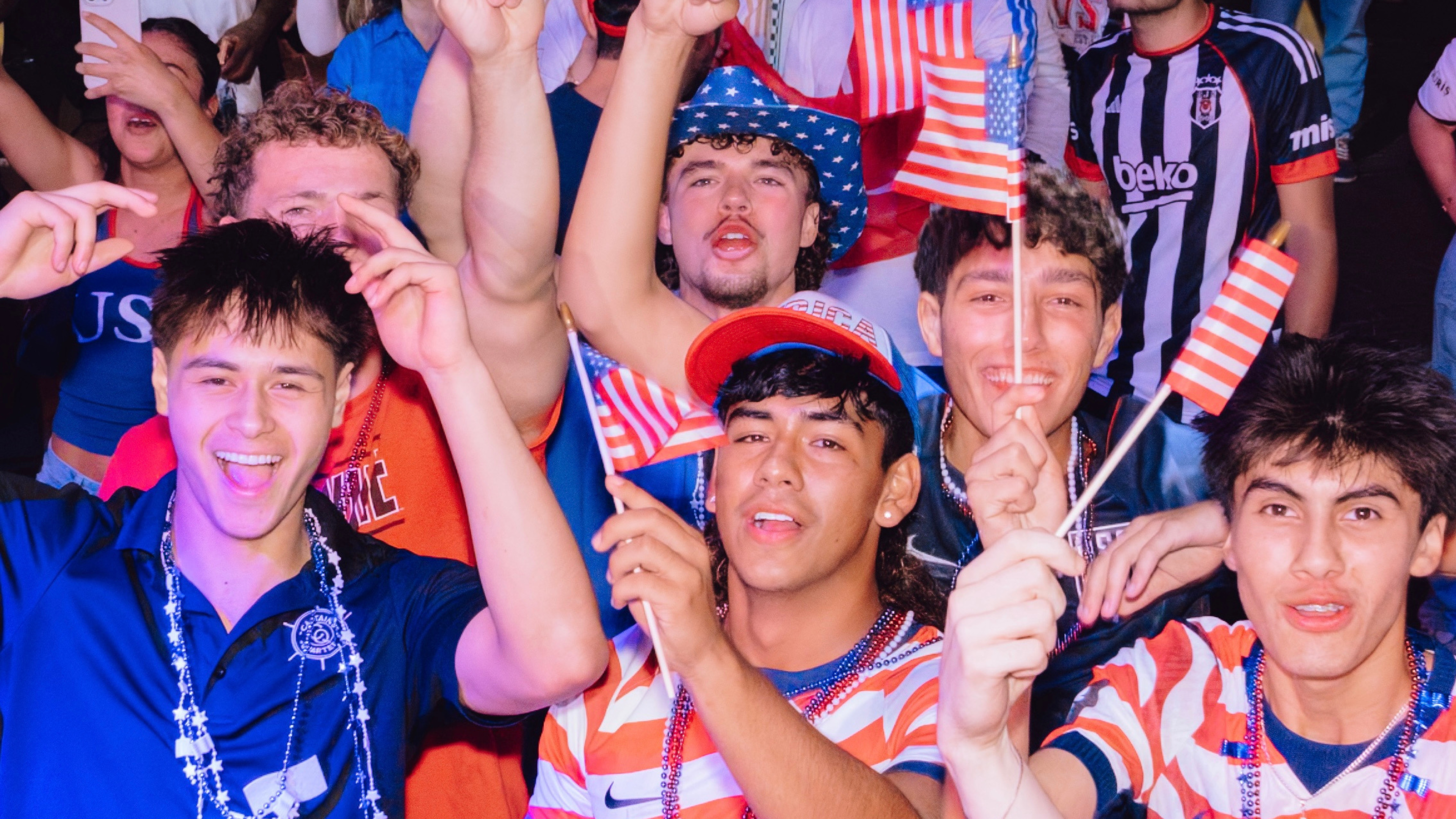 An image of USA fans cheering and holding mini USA flags.