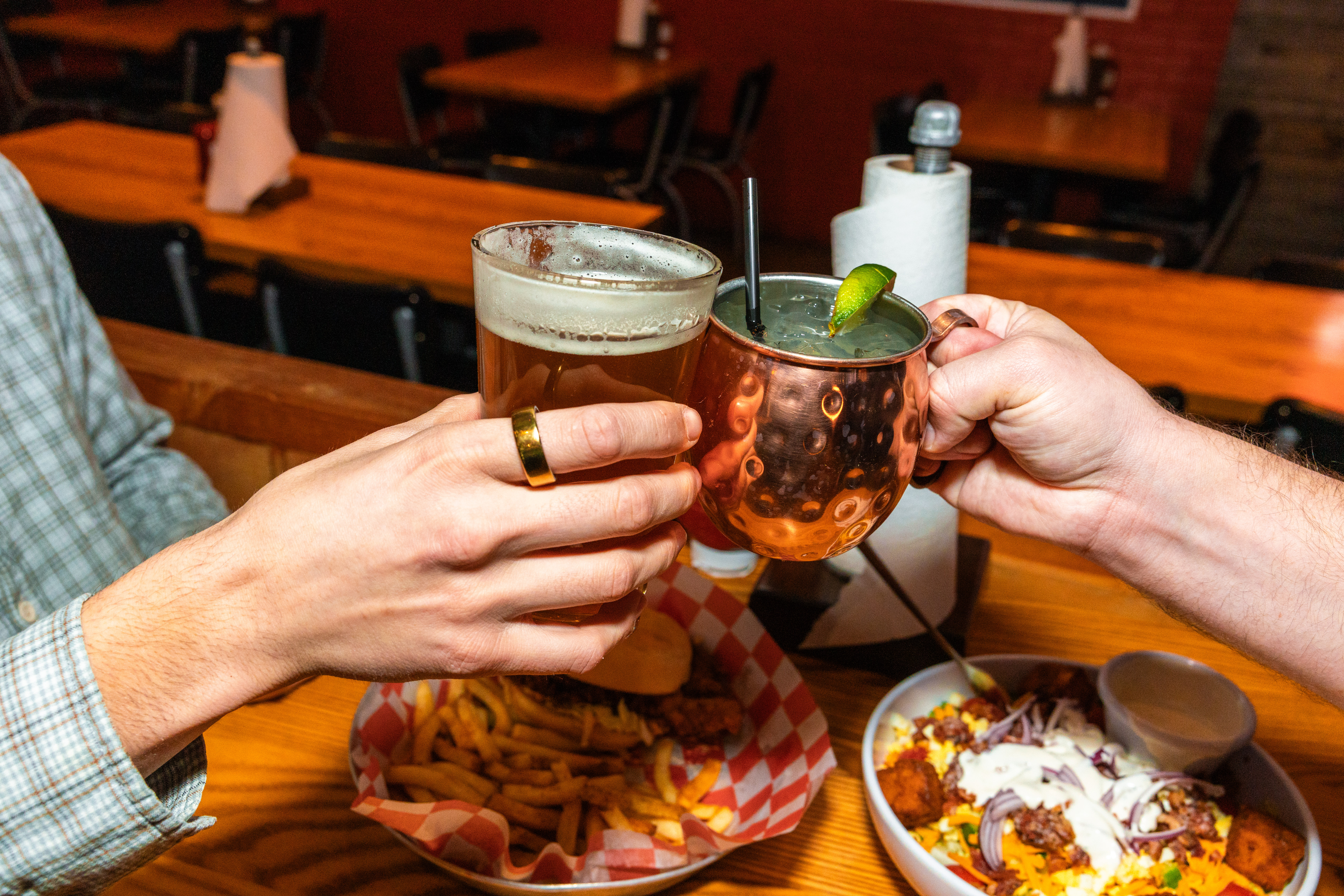 Two hands cheering a beer and a Moscow Mule at County Road Ice House