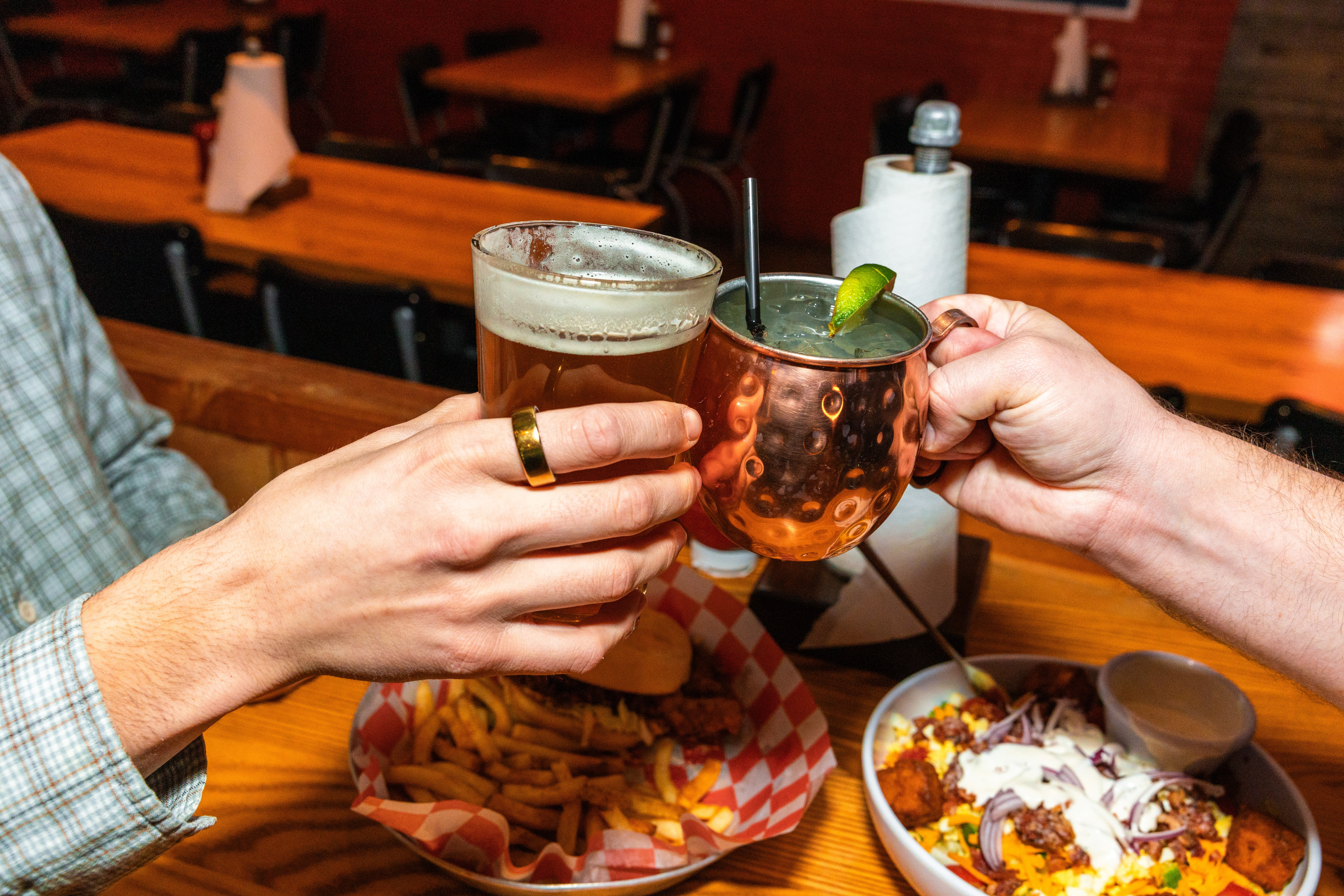 Two hands cheering a beer and a Moscow Mule at County Road Ice House