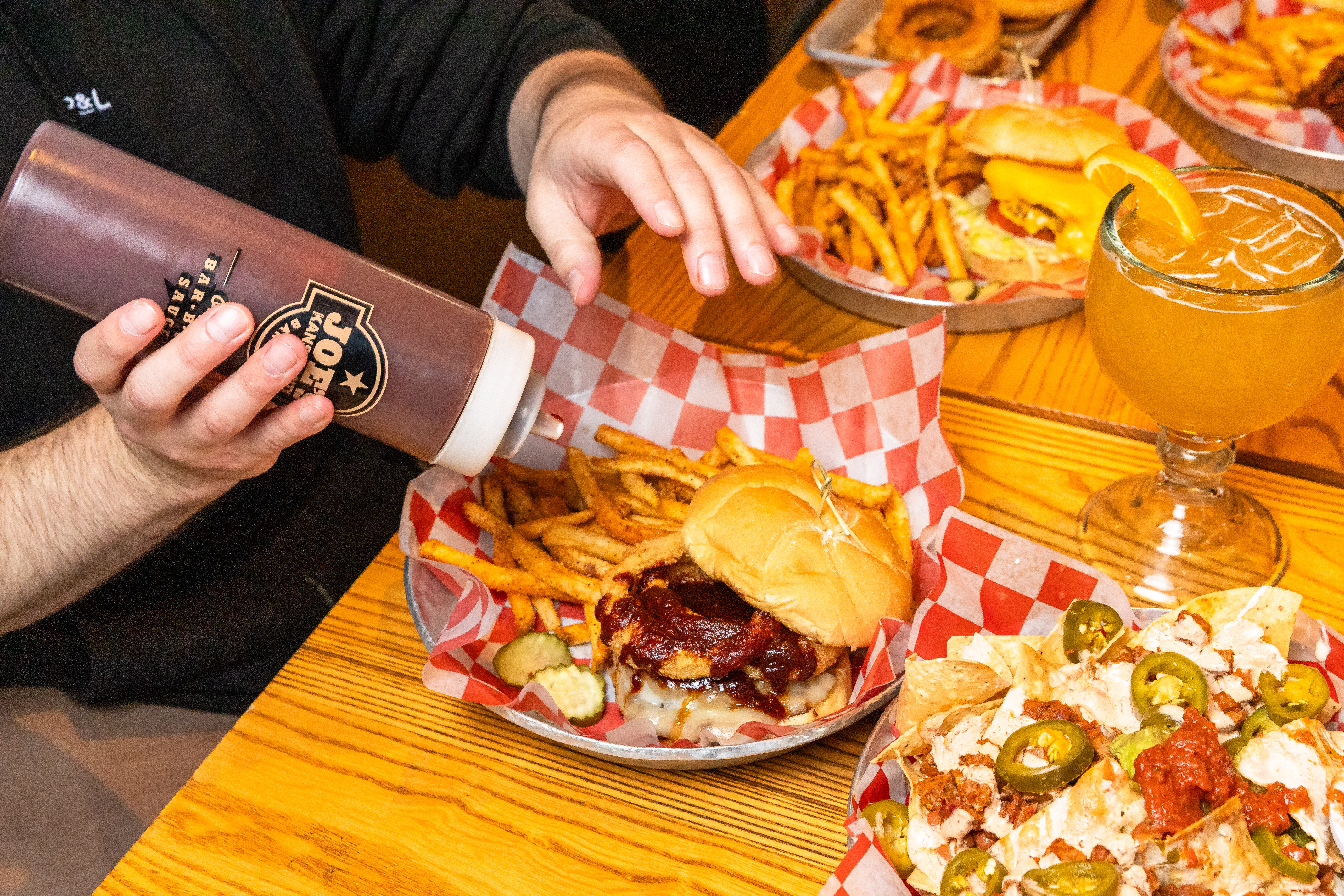 Man squeezing sauce onto a BBQ sandwich