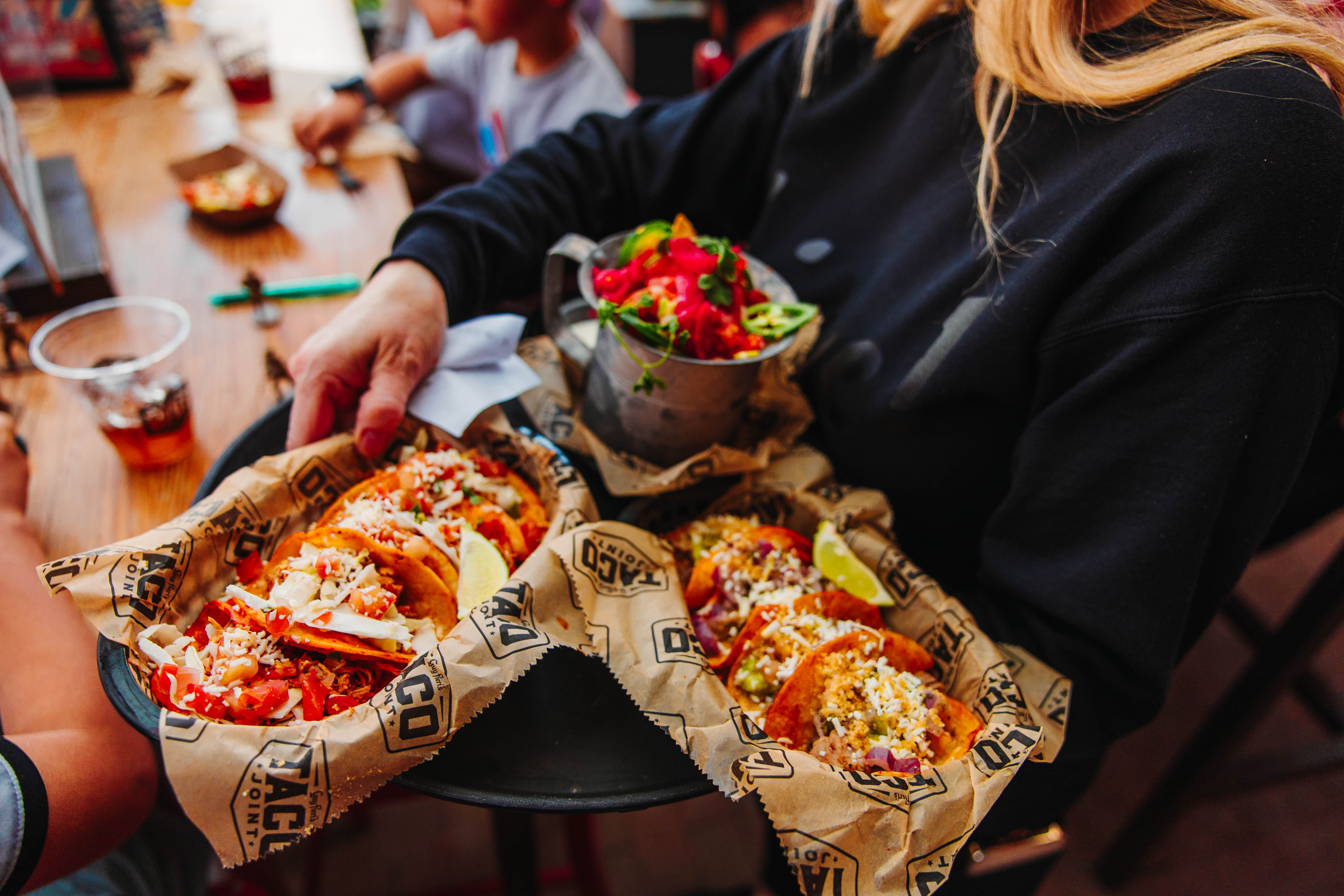 Server carrying tray with tacos and nachos