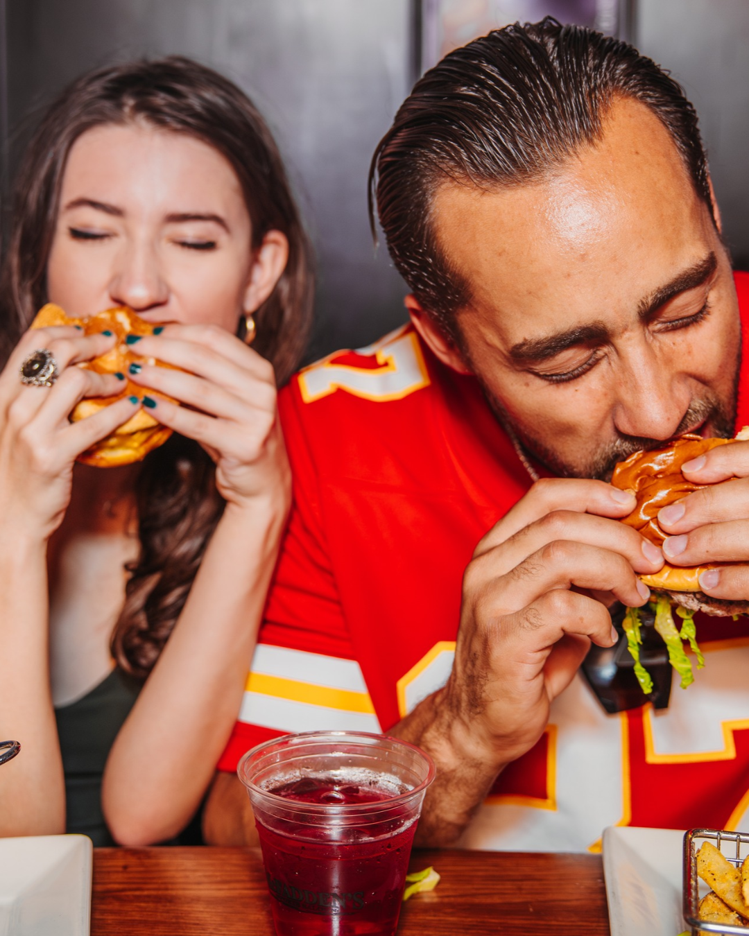 Two people sitting eating burgers