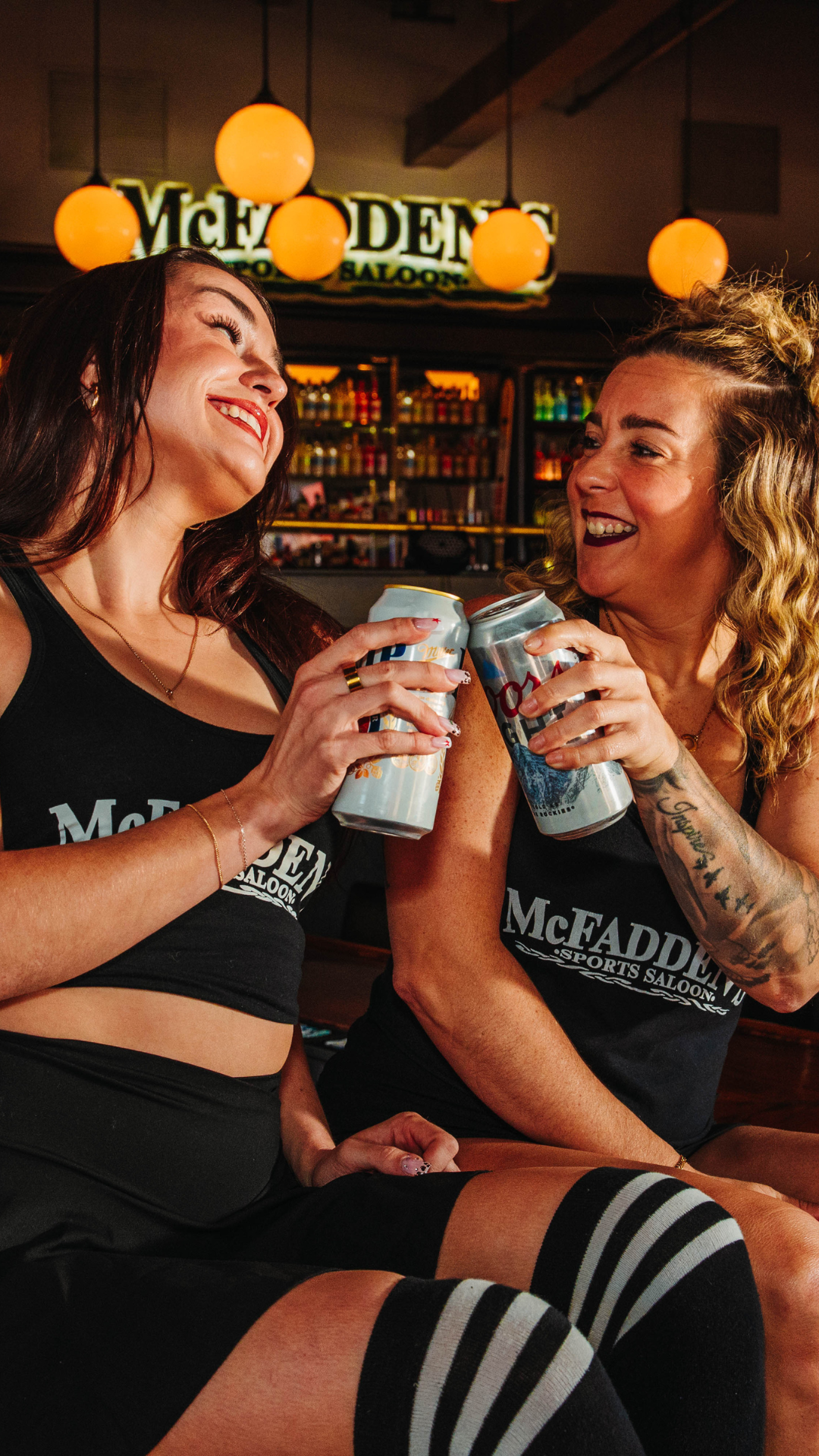 Two bartenders cheering cans of beer