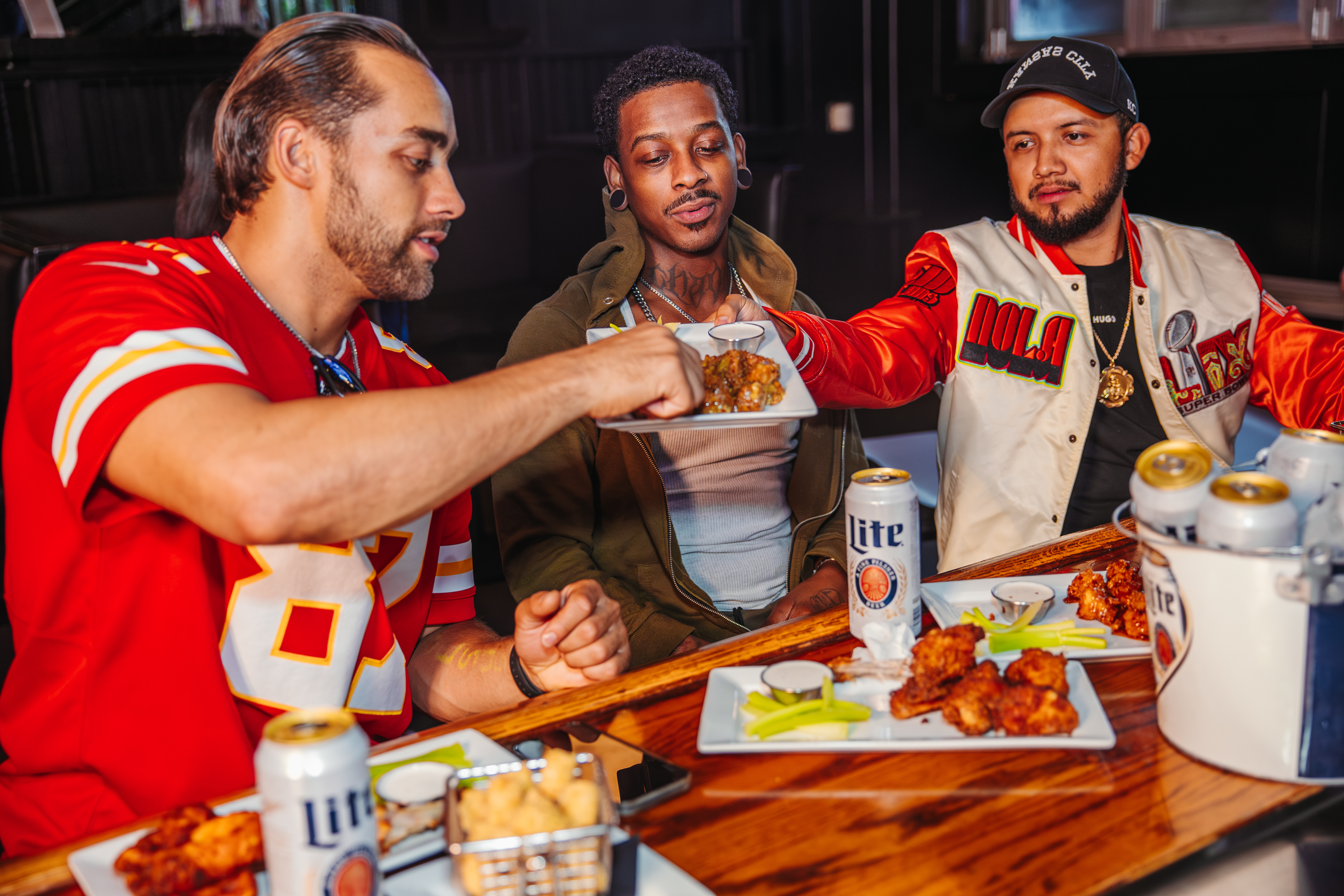 three male friends sharing plate of wings