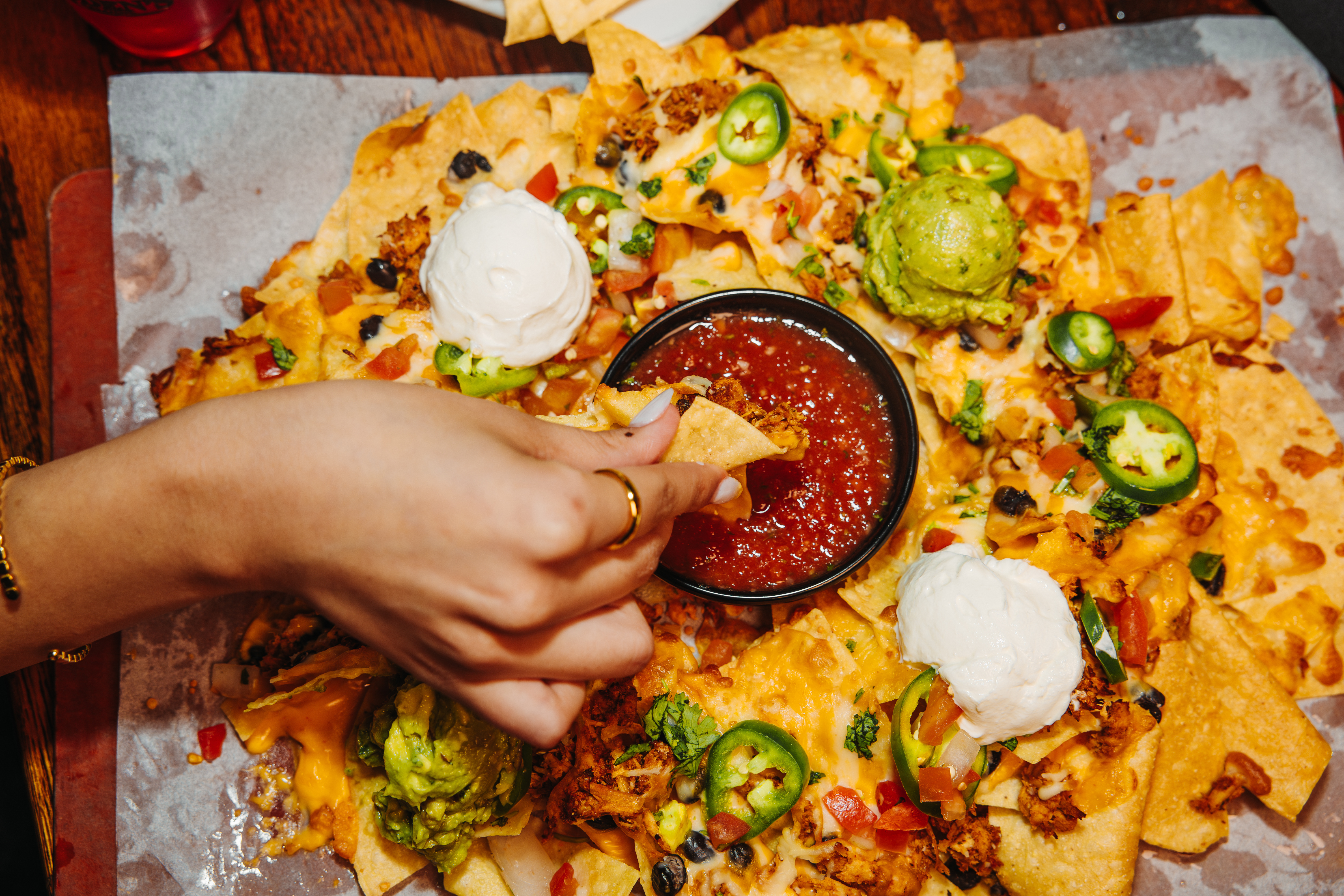 Hand dipping nacho chip into salsa