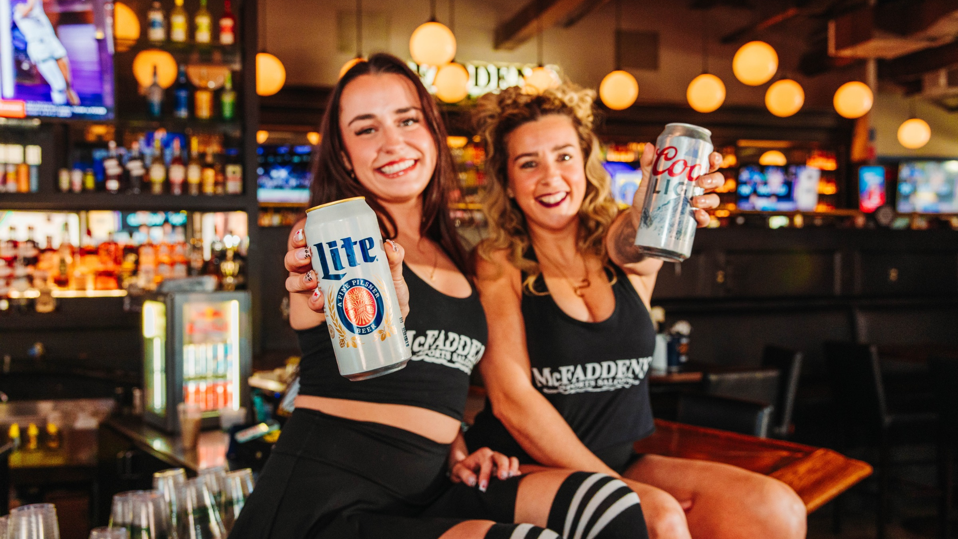 Two women holding cans of Miller Lite and Coors Lite