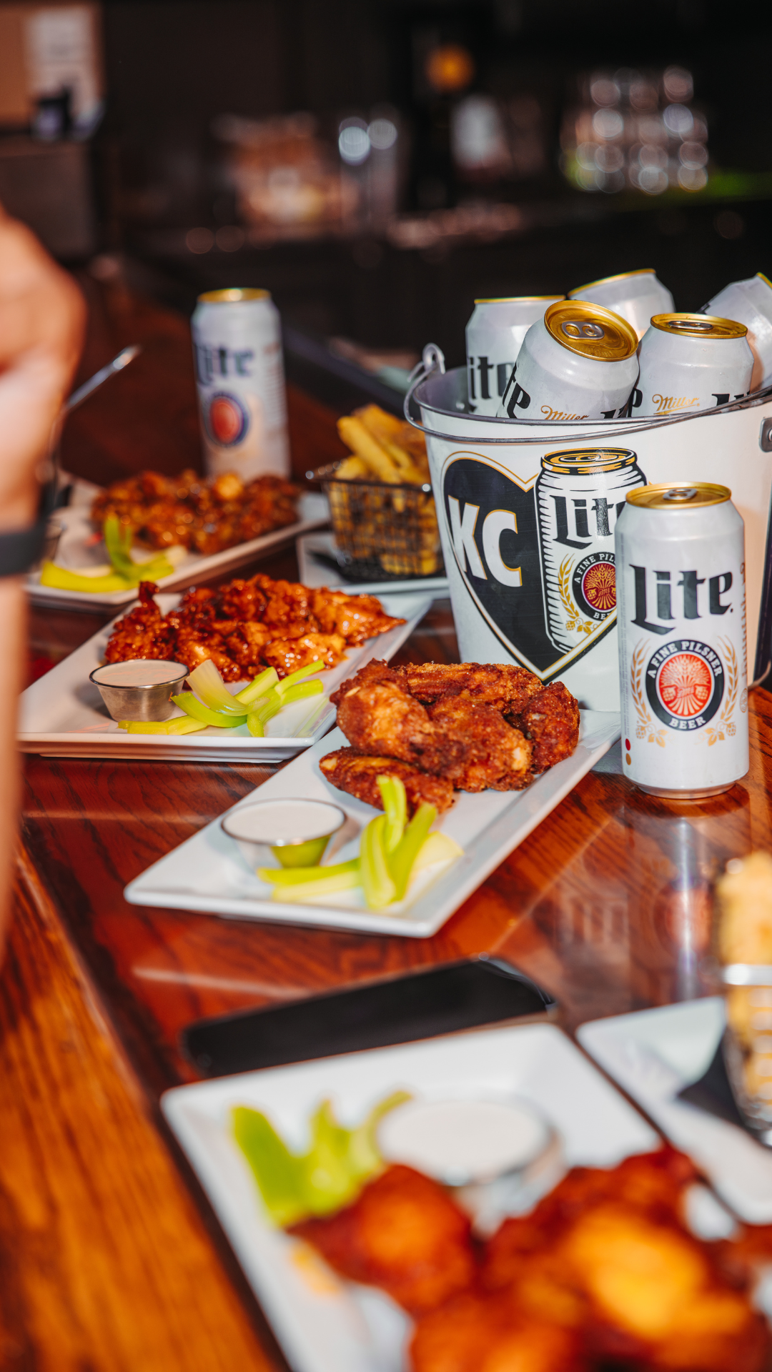 Plates of wings and a bucket of beers on a bar top