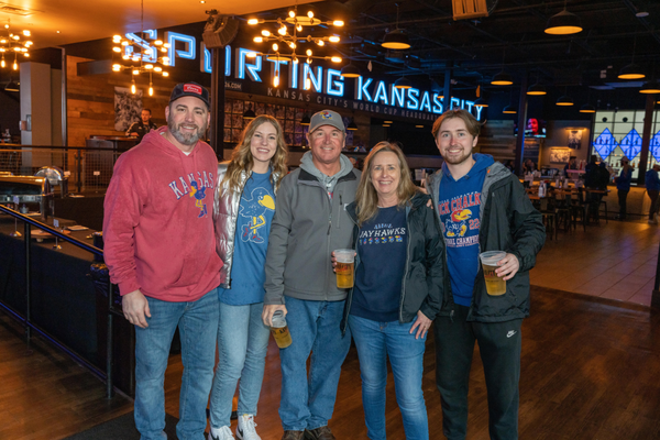 Four people wearing KU gear standing in No Other Pub