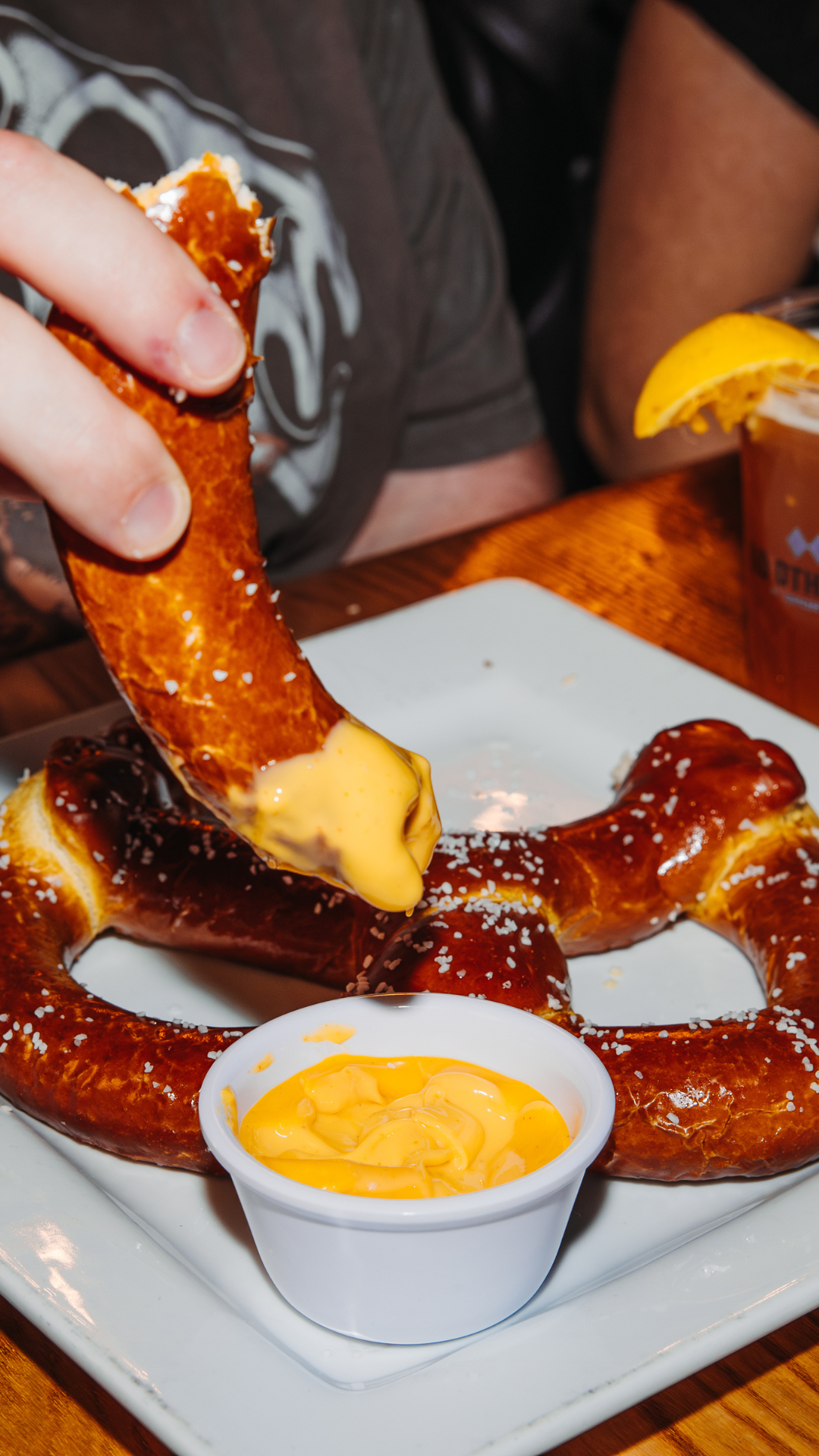 Hand dipping pretzel into cheese dip