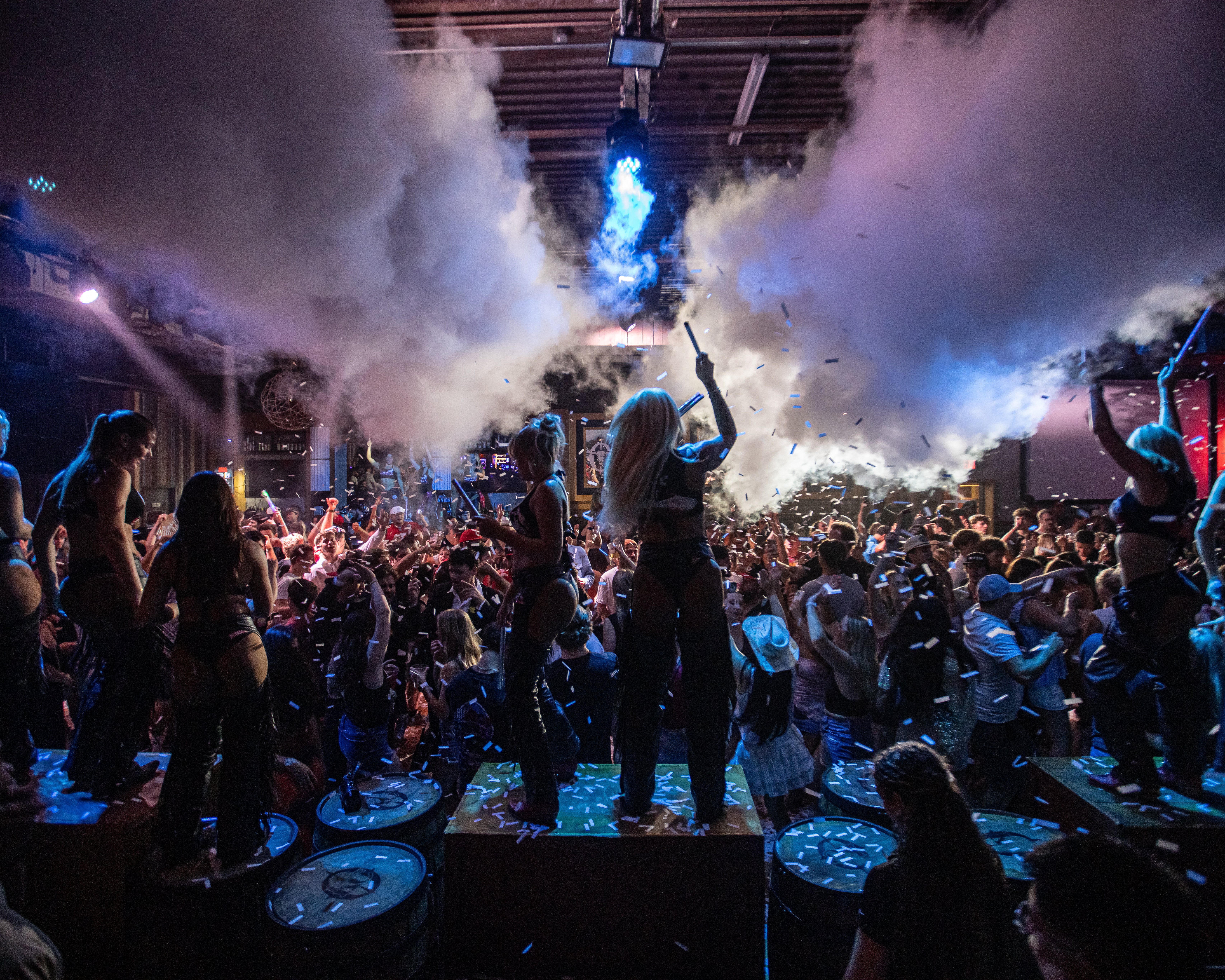 PBR Blackout: Buckle Bunnies dancing on platforms with fog machines, confetti, and dancing for large crowd