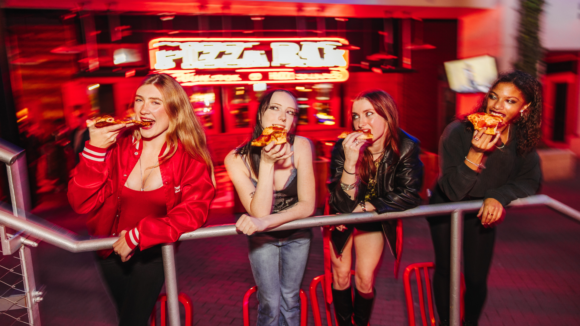 Four women standing in front of Pizza Bar eating pizza