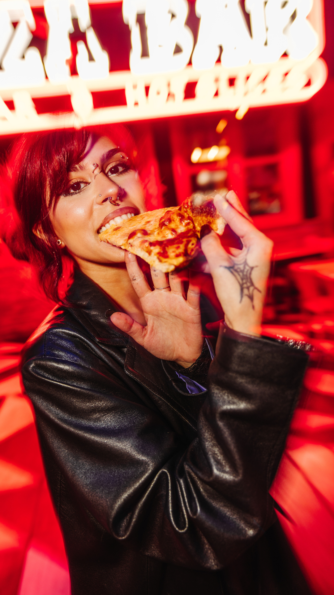 Woman standing outside of Pizza Bar eating a slice of pizza