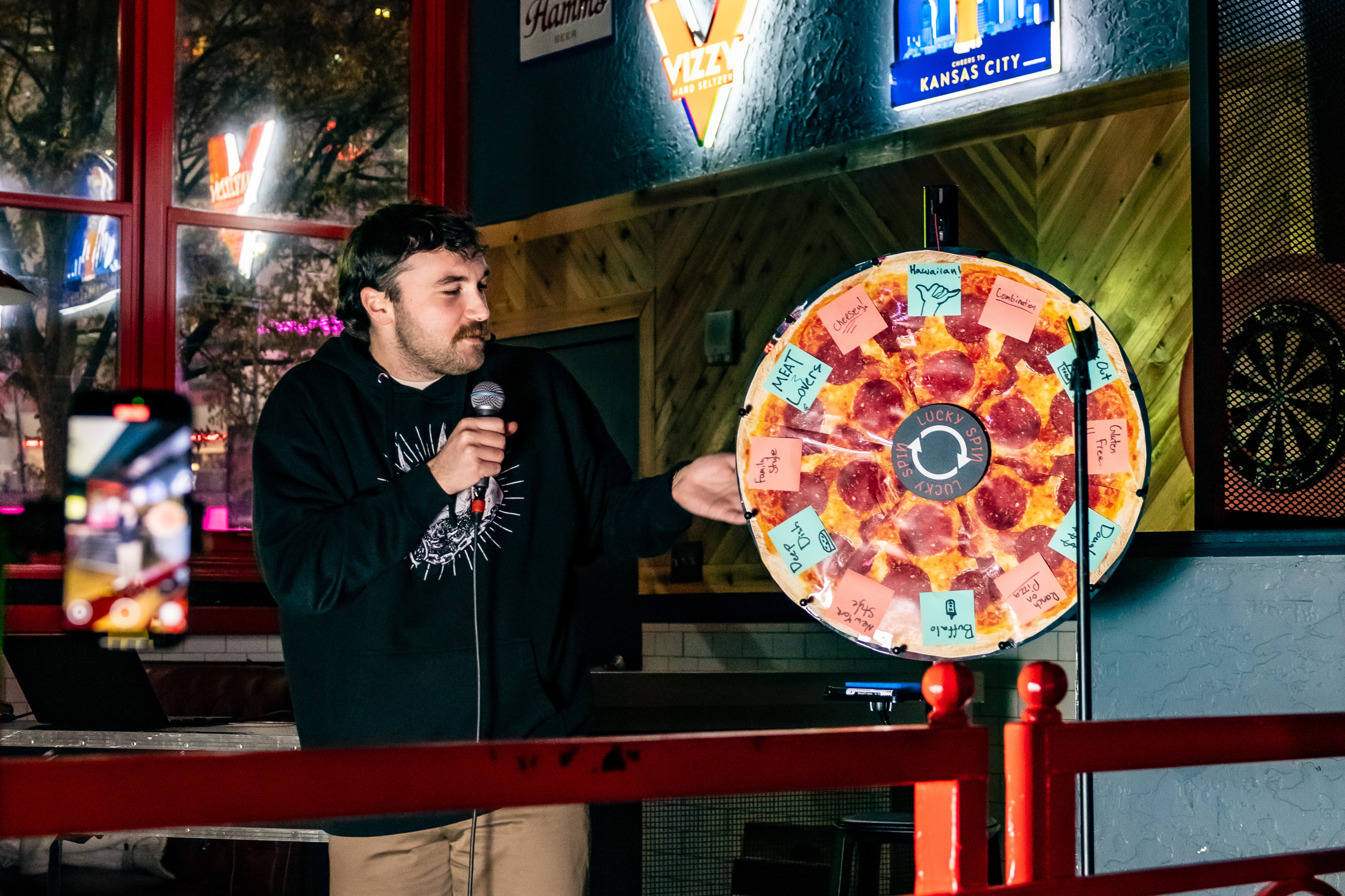 Man standing next to a pizza spinning wheel