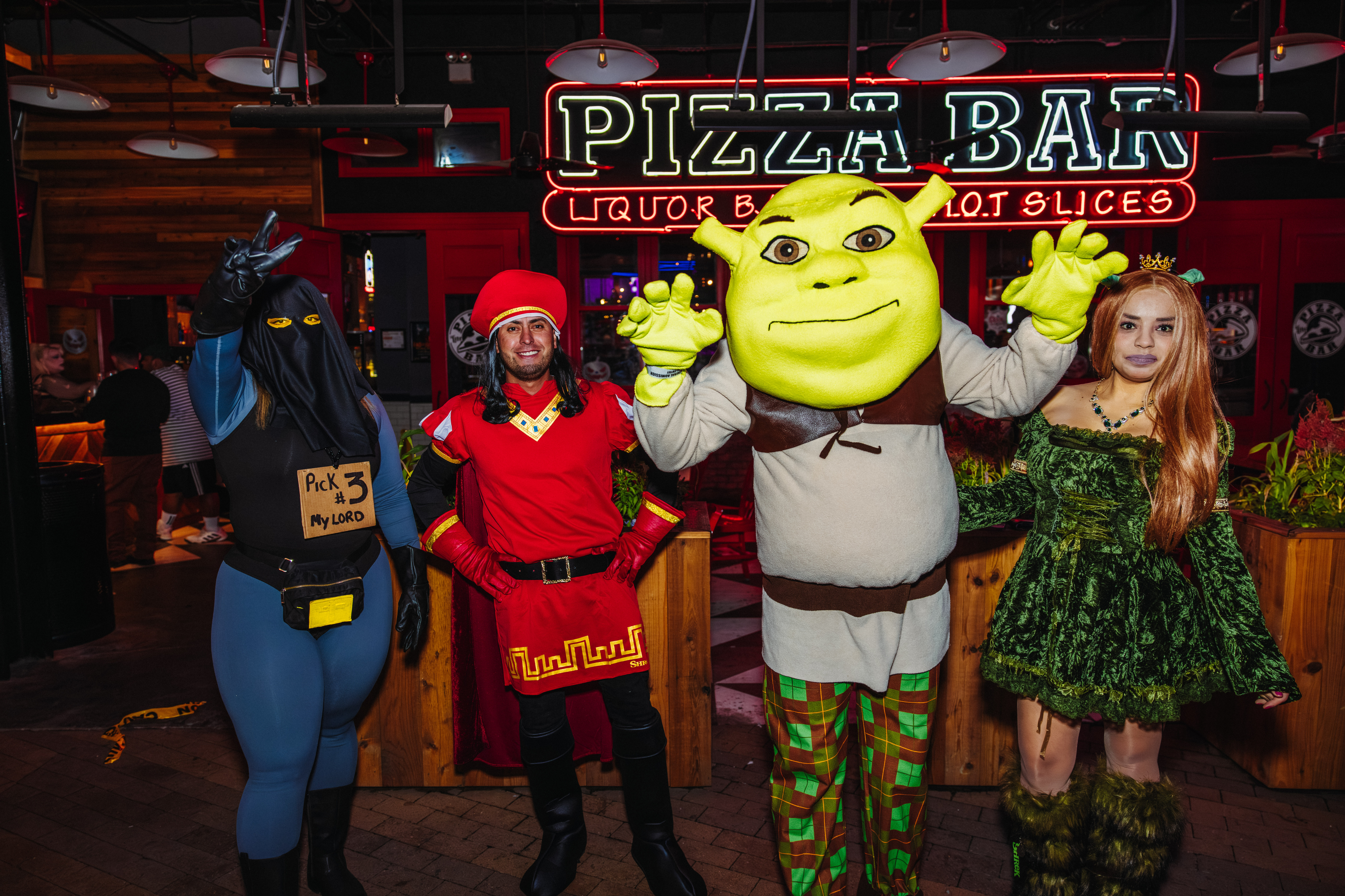 Four people in Halloween costumes outside of Pizza Bar
