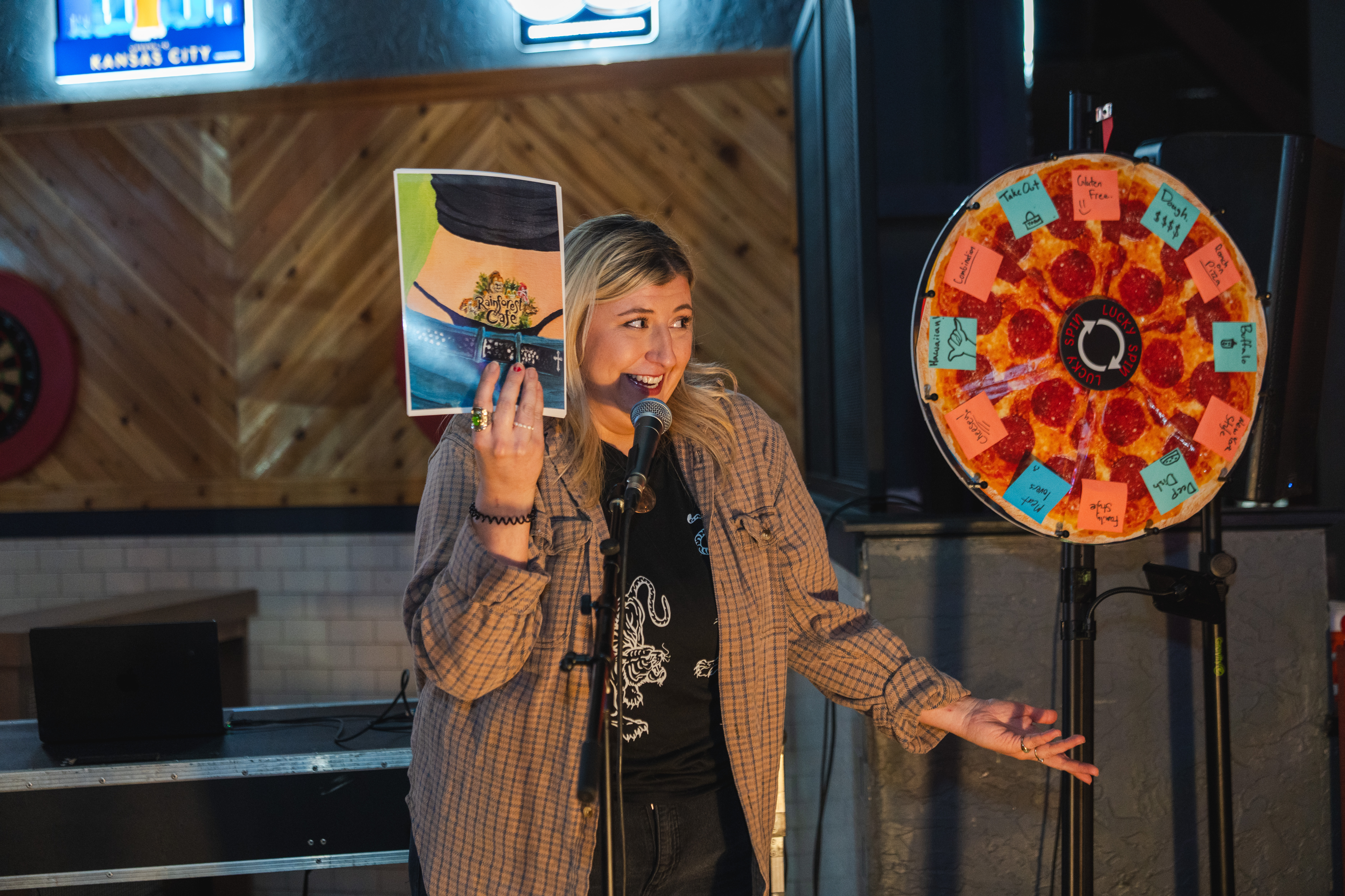 Woman standing next to a pizza spinning wheel holding a picture