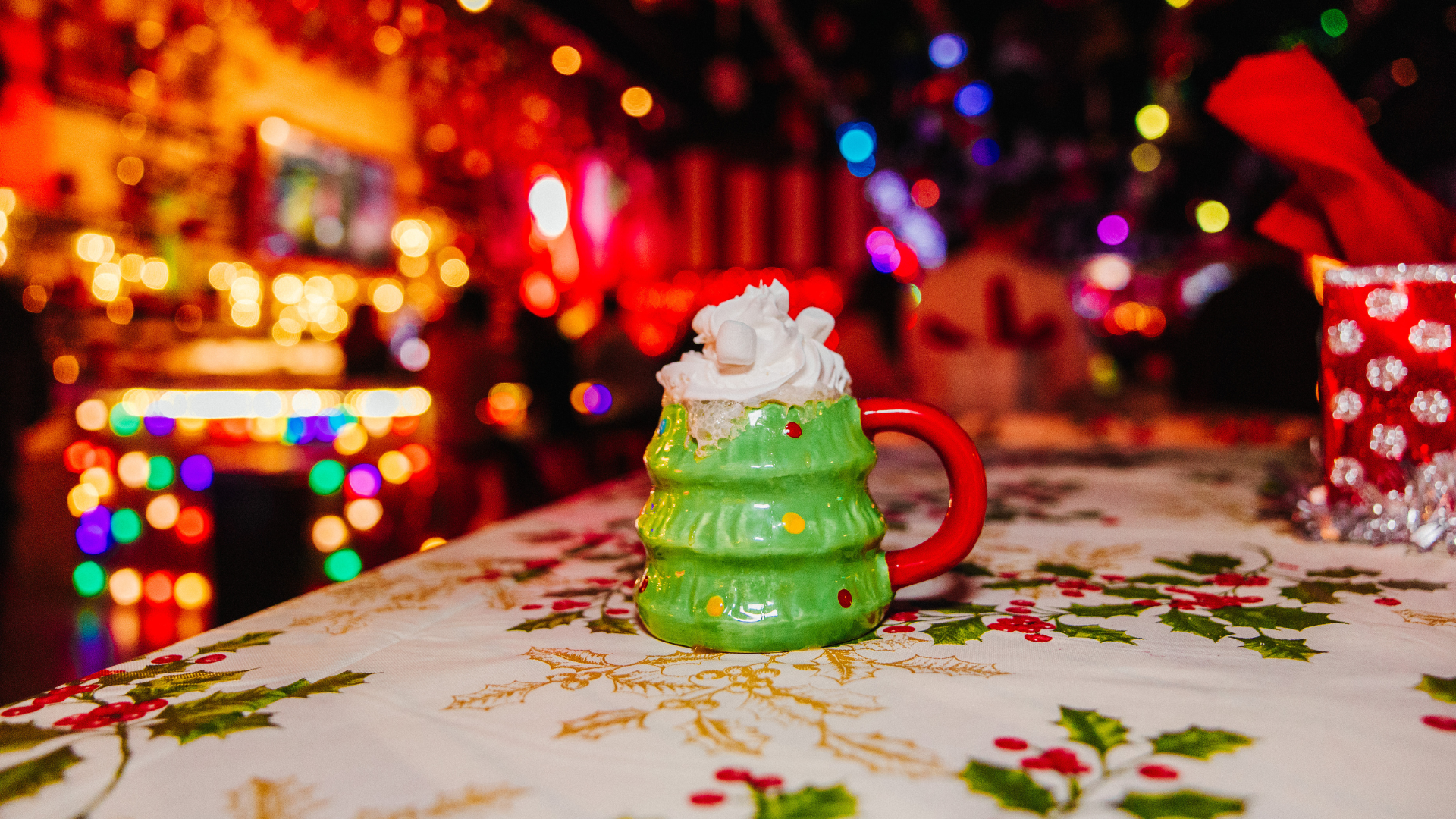 Christmas tree shaped mug on a table with Christmas decor in the background