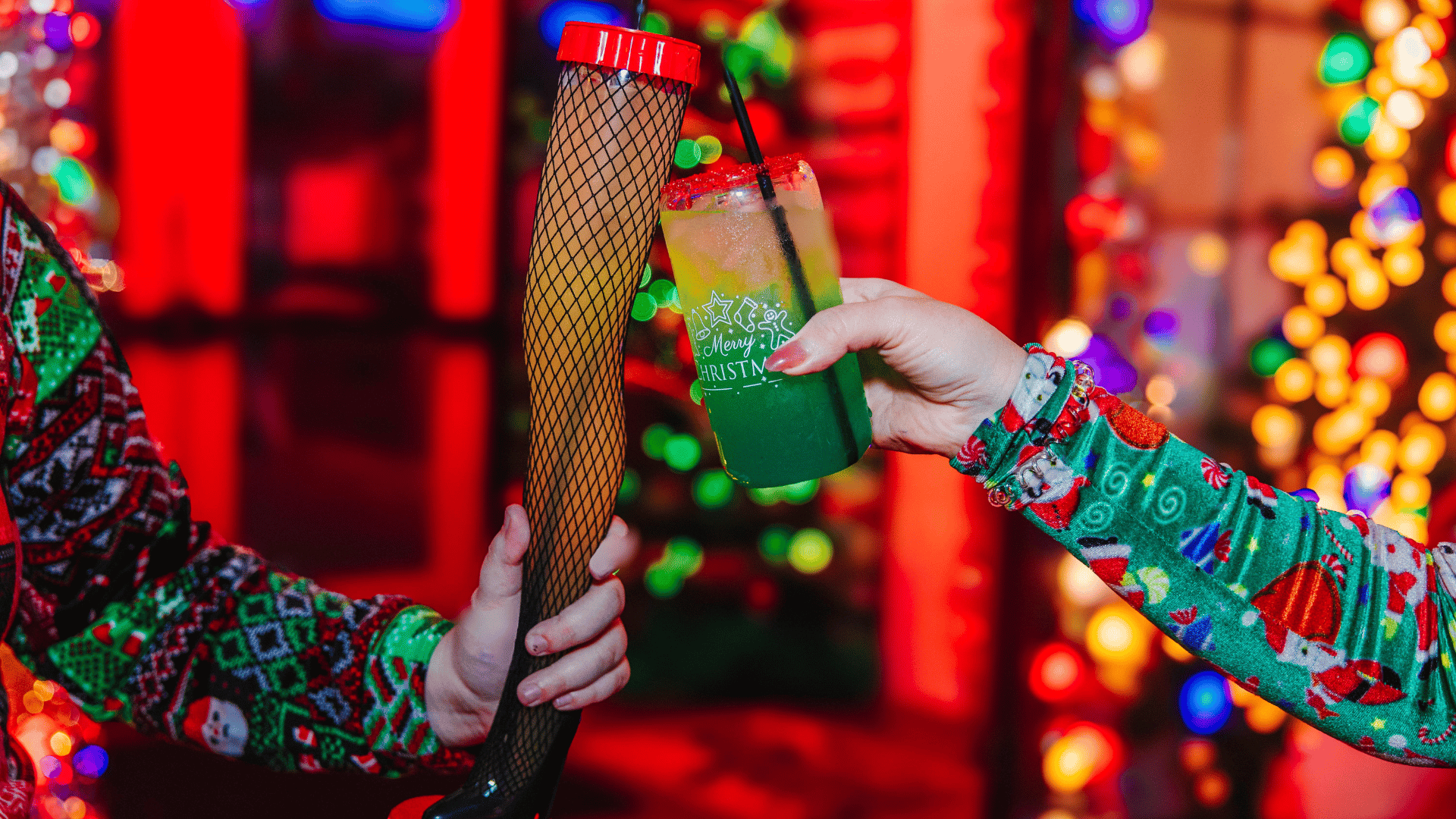 Two hands cheering Christmas themed cocktail glasses