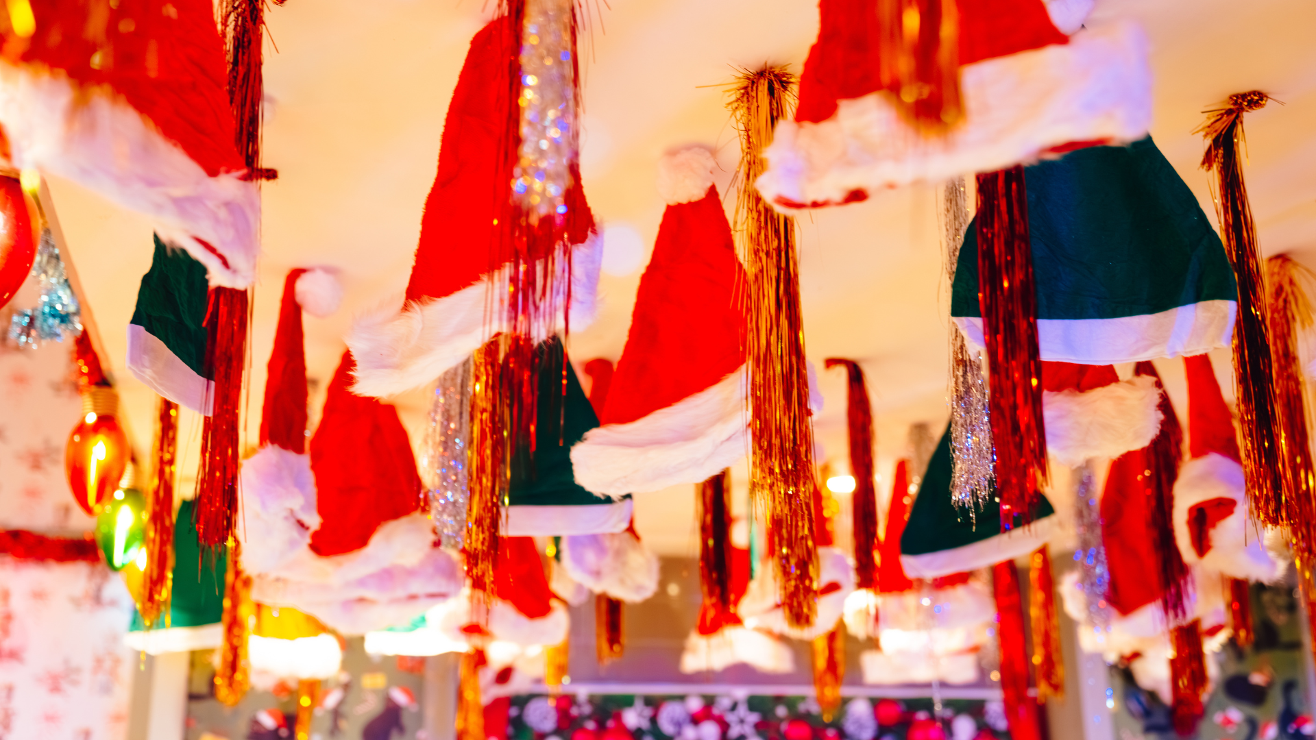 Santa hats and tinsel hanging from a ceiling