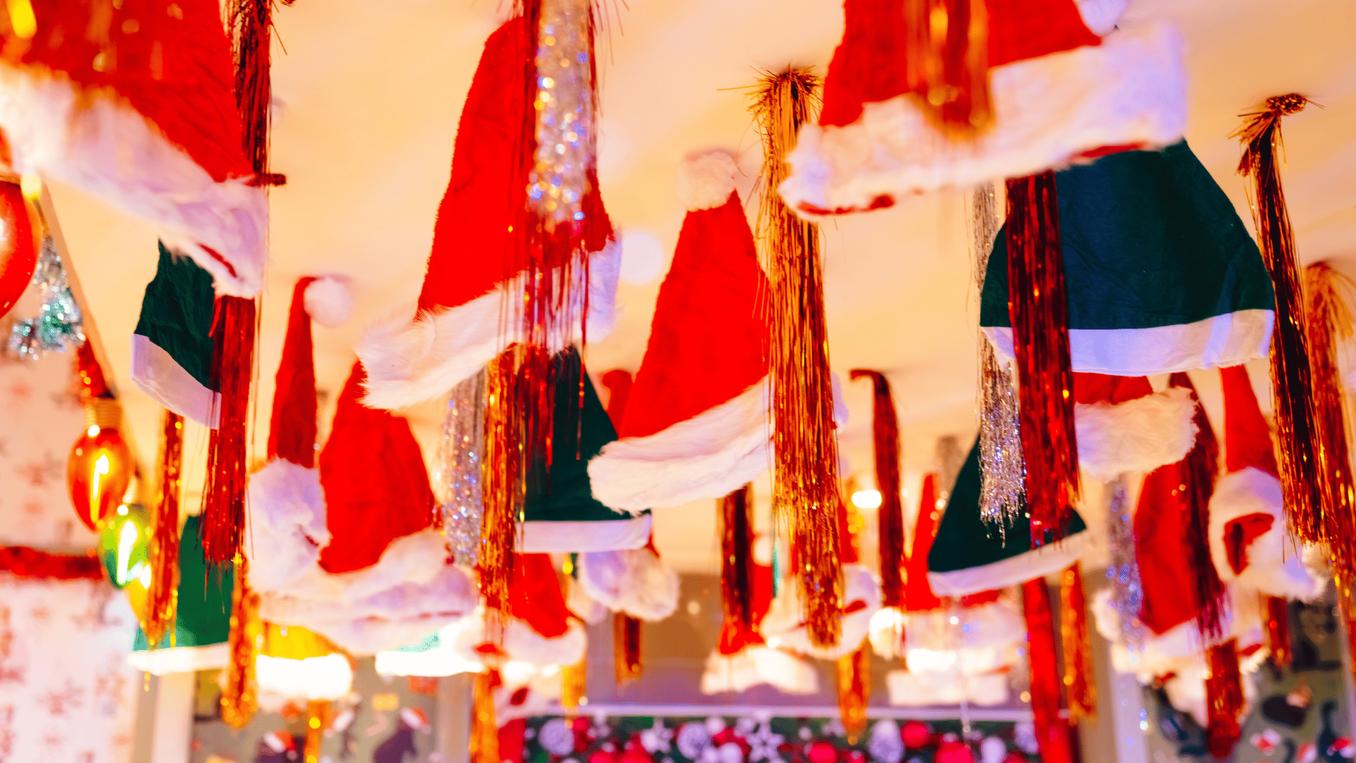Santa hats and tinsel hanging from a ceiling