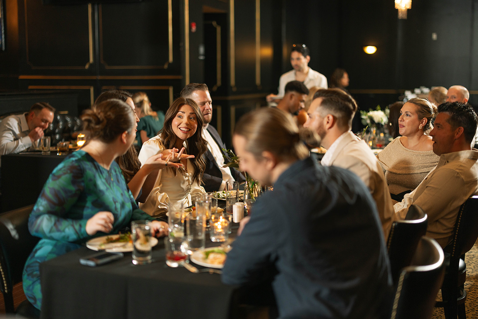 A group of people sit inside KDC with plated dinners for a wedding reception.