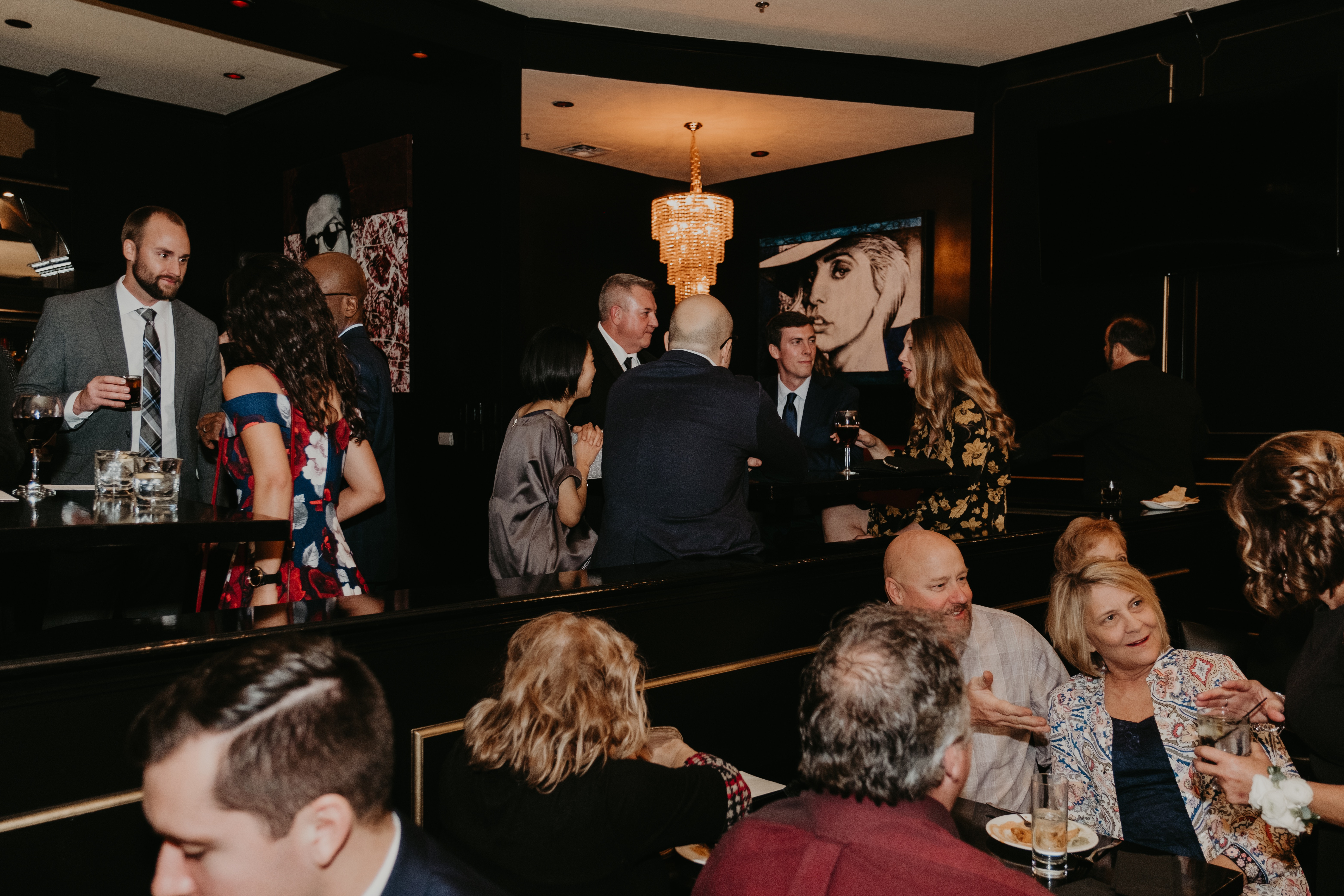 Guests at KDC sit at tables and stand at the bar.