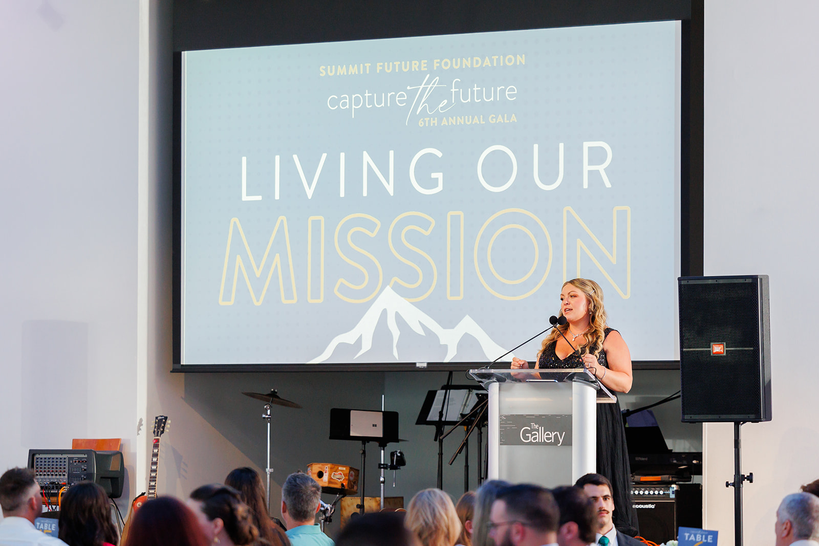 A woman speaks on the stage at The Gallery during a corporate event.