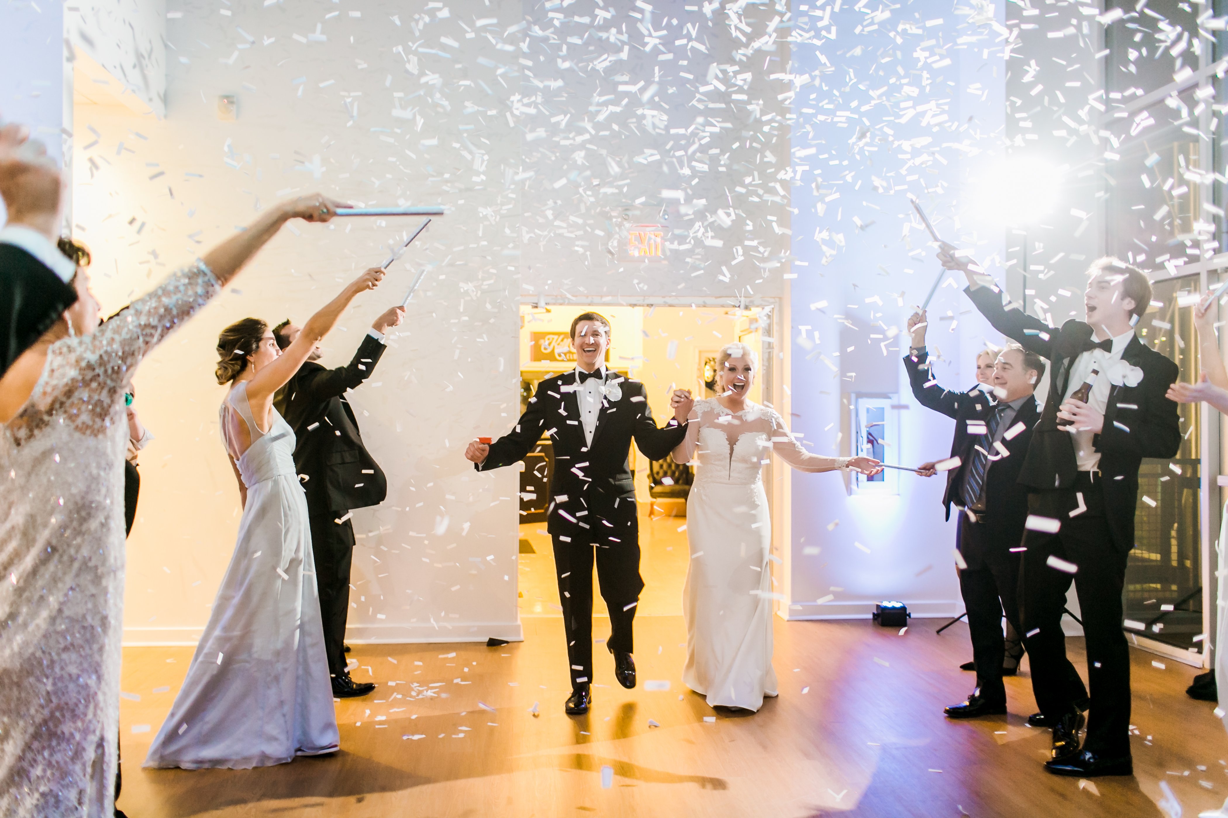 Bride and groom enter The Gallery as the crowd pops confetti poppers.