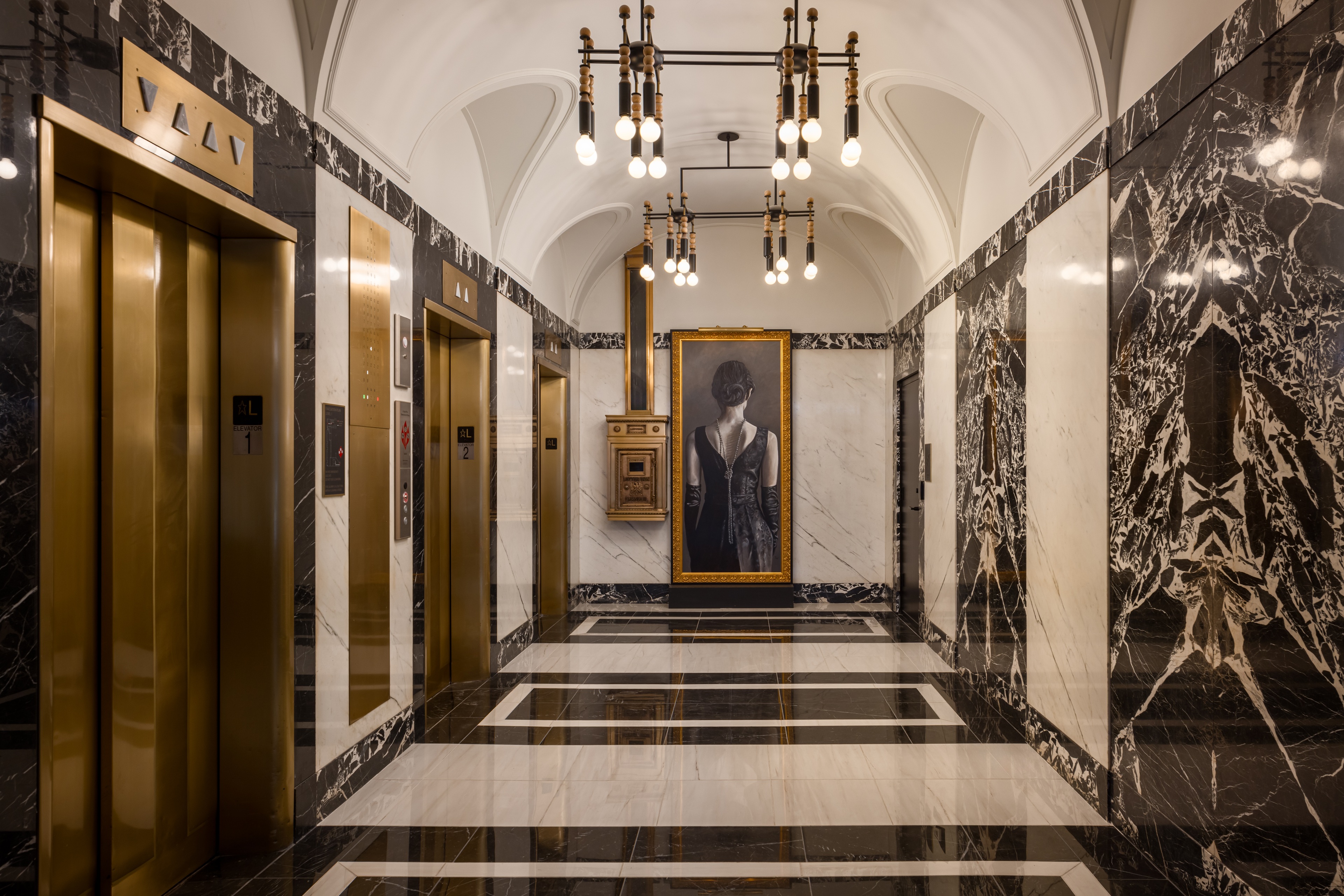 Gold elevators in black and white marble hallway at Midland Lofts Luxury Apartments.
