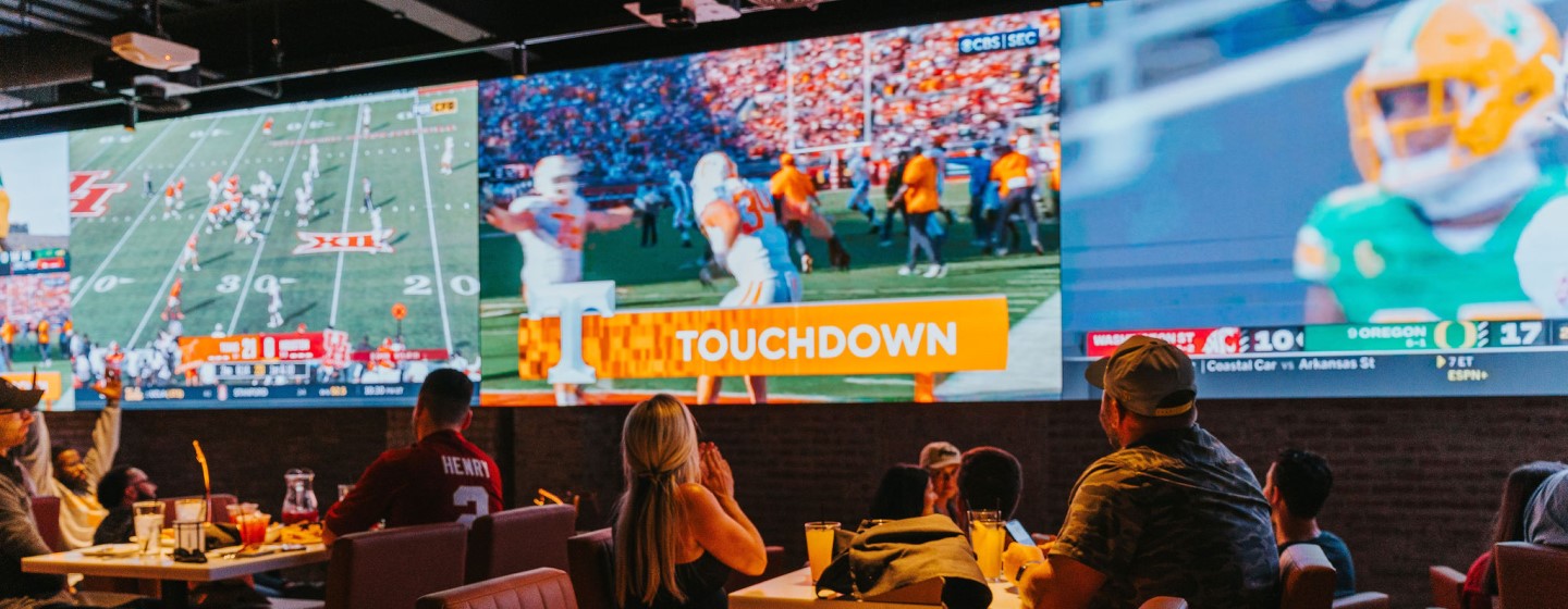 Big screen tvs and guests dining at tables at DraftKings Sports & Social, Nashville Live!