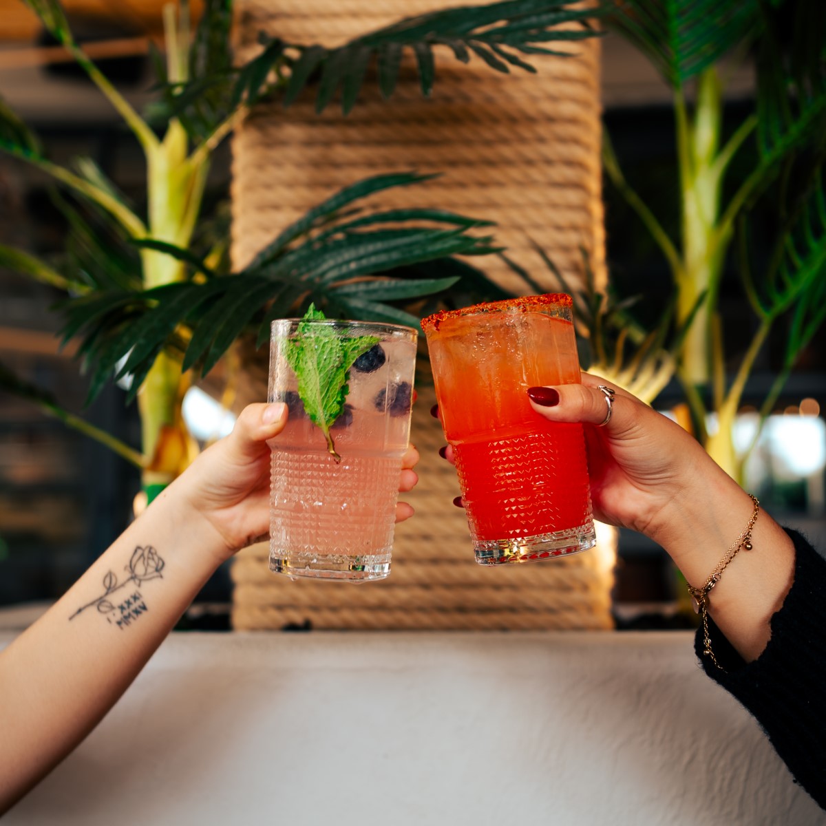 Two fruity cocktails in large glasses being toasted.