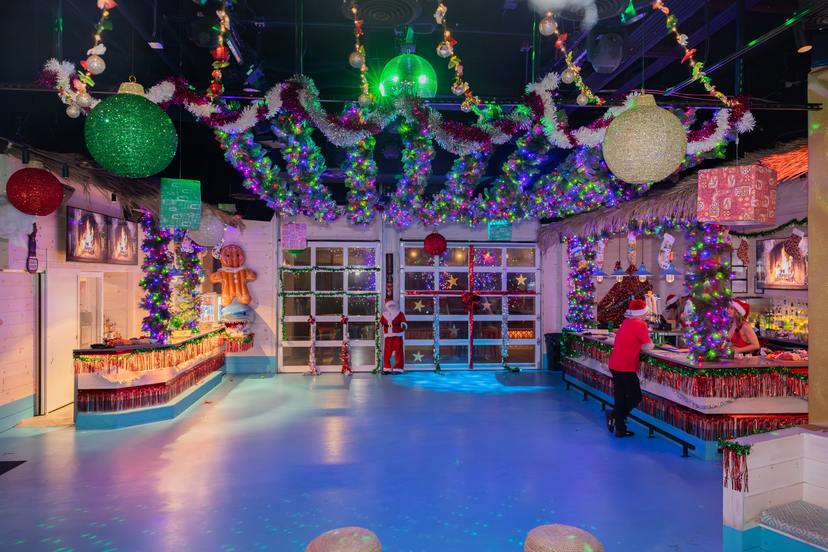 Shark Bar bar and dance floor area decorated for the holidays with large ornaments and garland hanging from the ceiling.