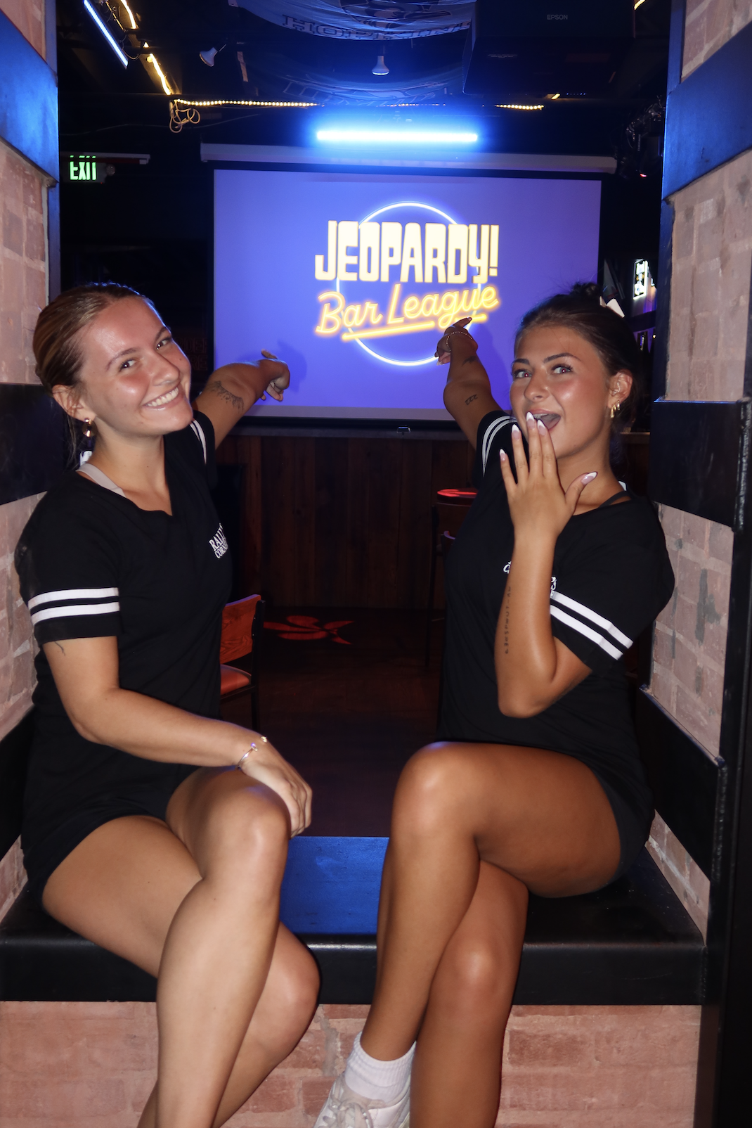 two rally's team members pointing at the Jeopardy Bar League sign