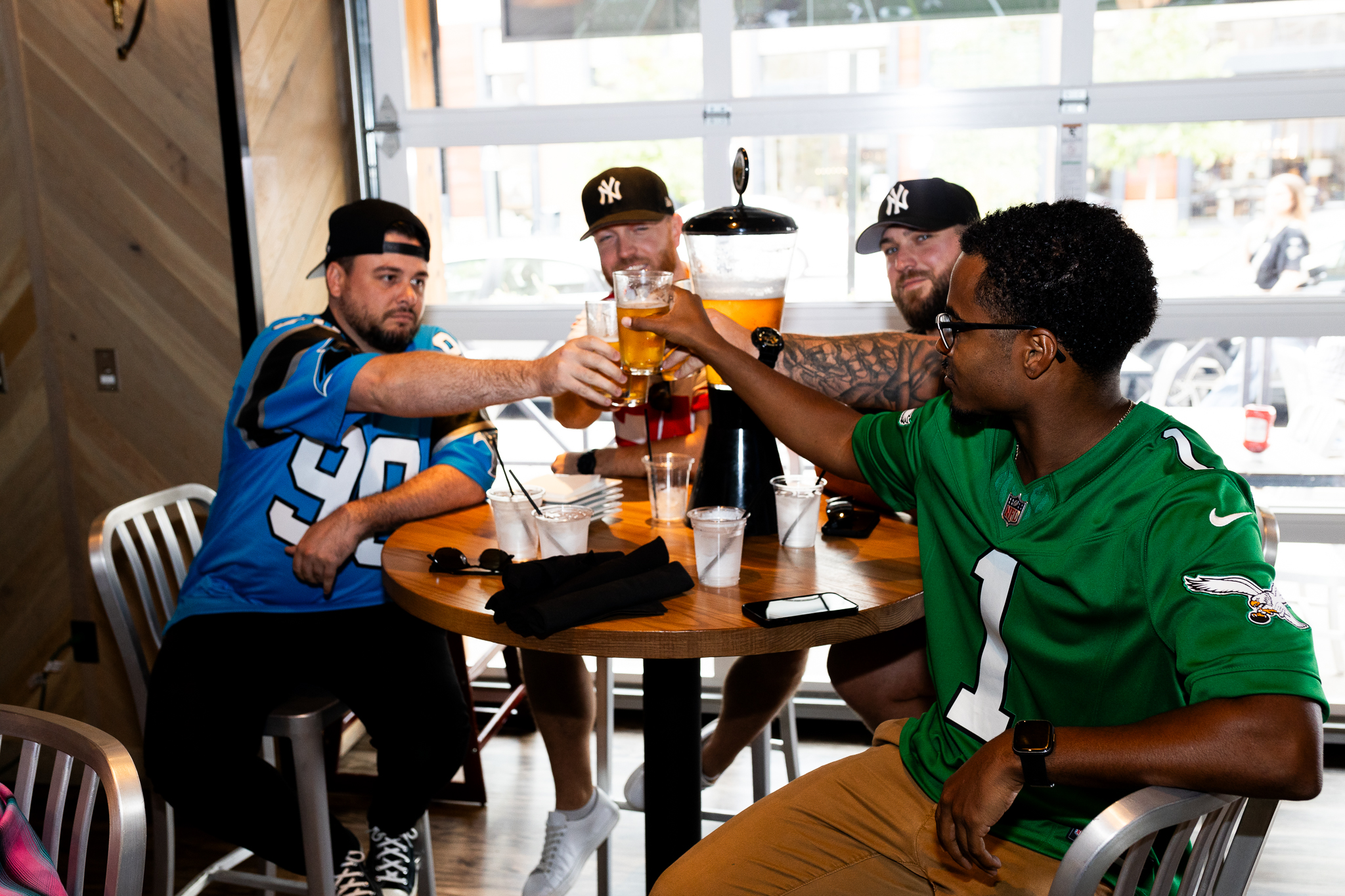Four men toasting beer at a sports bar.