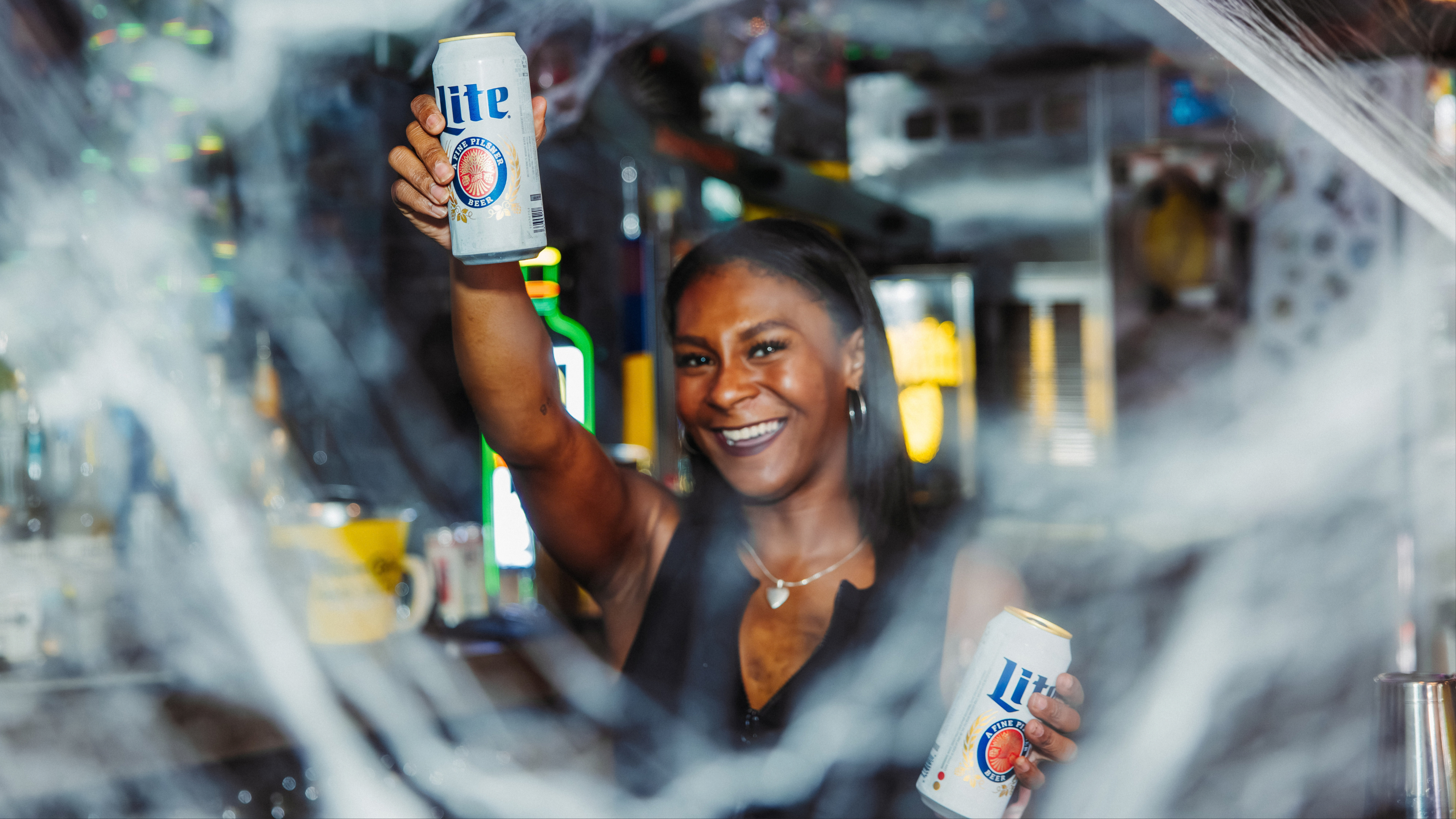 Bartender holding two miller lite cans with cobwebs