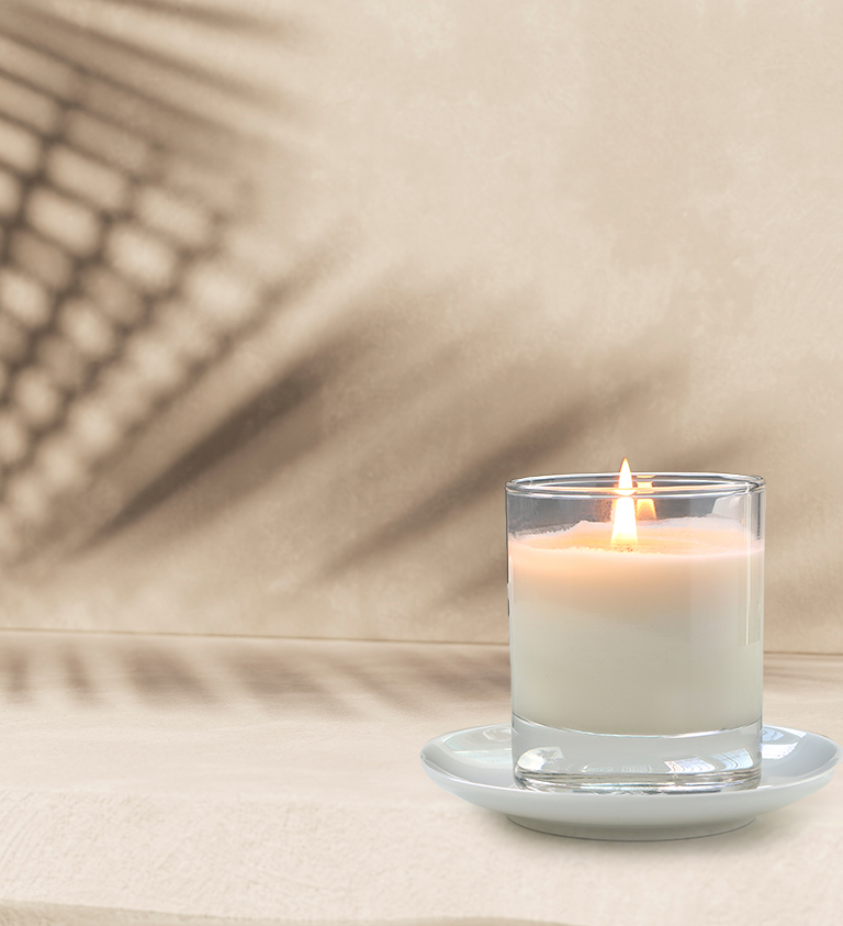 white candle, lit, on a cream background