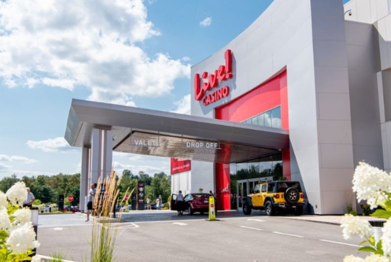 The Live! Casino valet drop-off is under a covered roof and leads to glass doors bordered by a red accent wall.