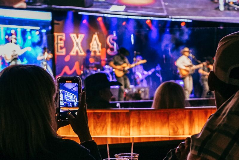 A fan holds up her phone to capture the moment as a band plays on the Texas Live! stage.