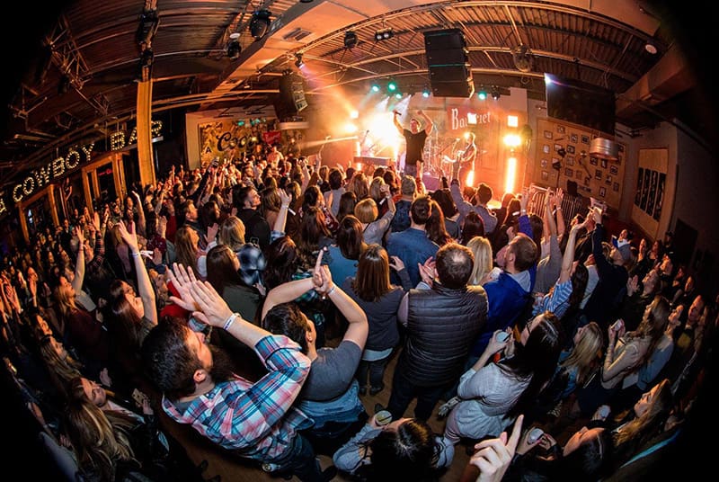 A lead singer riles an excited PBR Cowboy Bar crowd up as his band plays behind him!