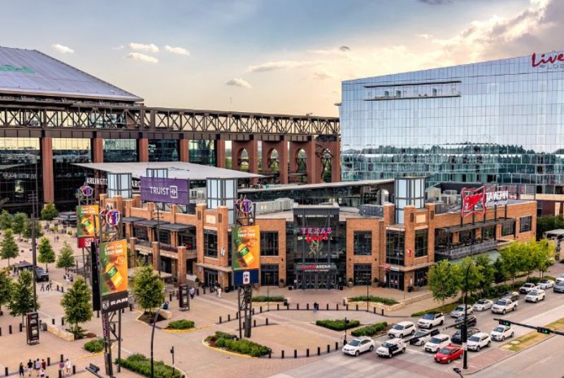 Outside of beautiful Texas Live!, featuring a tall mirrored Live! by Loews hotel that reflects structures and skies.