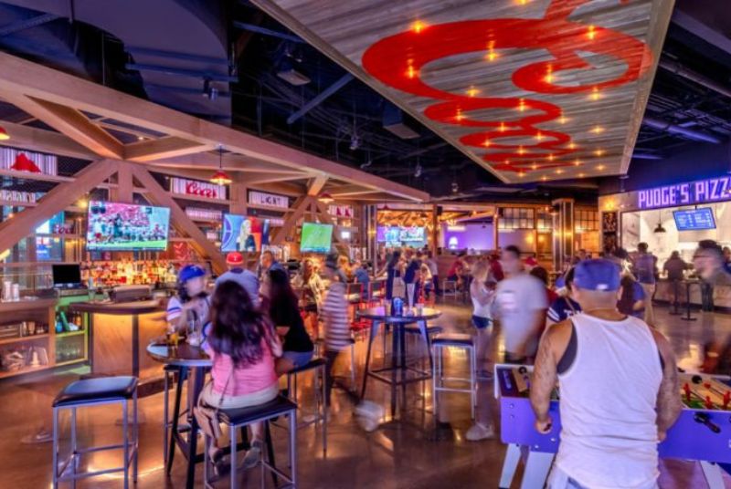 At the front bar in Sports & Social, a couple plays foosball while tables of customers enjoy some beers.