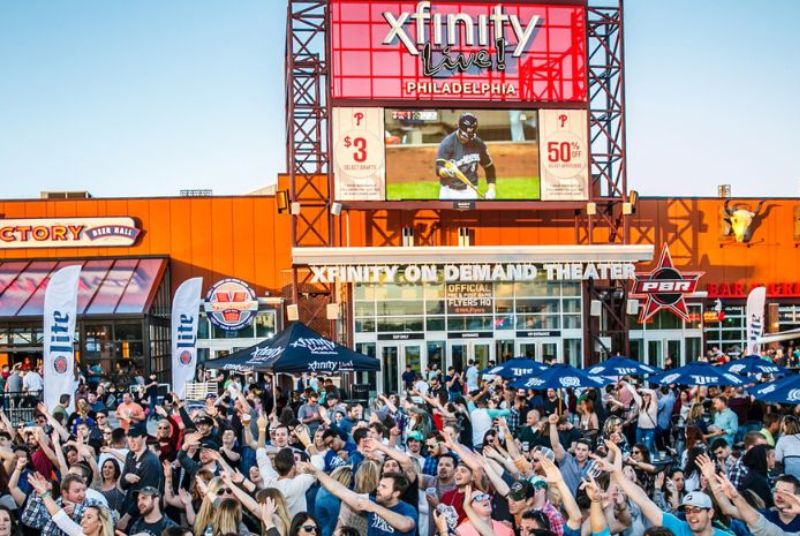 A smiling Springfest Live! crowd puts their arms in the air while others enjoy drinks in front of the PBR Bar & Grill.