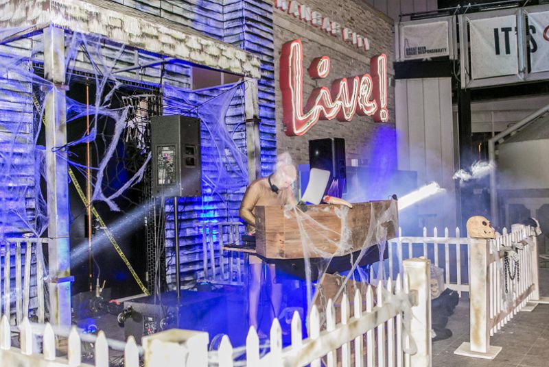 A zombie DJ spins Halloween tunes with a meat cleaver and severed hand resting in front.