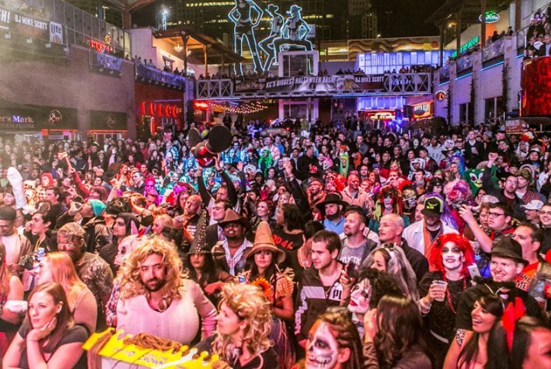 Witches, Gumby, and hundreds more celebrate Halloween in a smiling crowd.