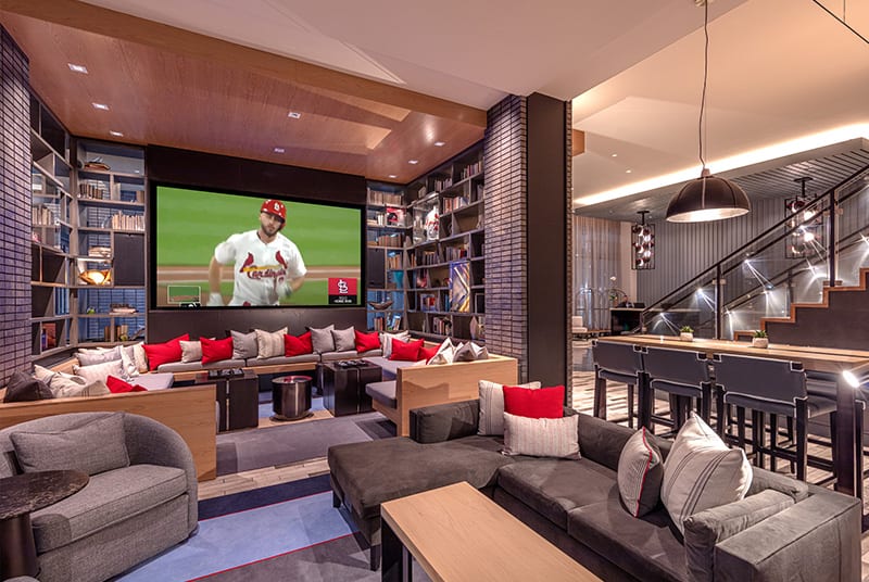 A comfy lounge full of cushioned seats and stylish sectionals offer a great view of the Cardinals game on a large LED screen.